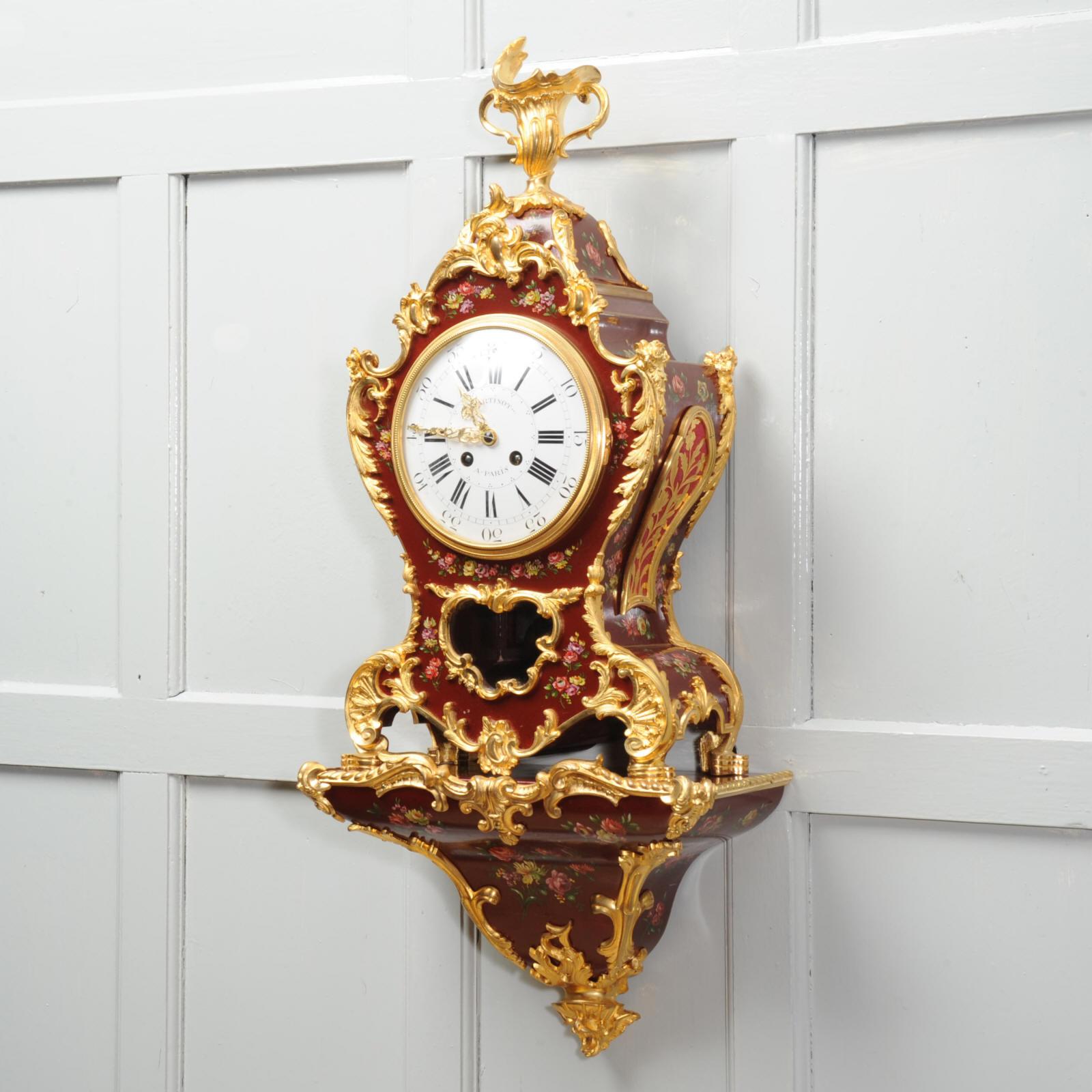 A large and stunning antique Rococo Style bracket clock with it's original bracket. Classic Rococo shape in exquisite Vernis Martin style red lacquer, painted with delicate floral swags and mounted with crisp ormolu (finely gilded bronze) mounts.