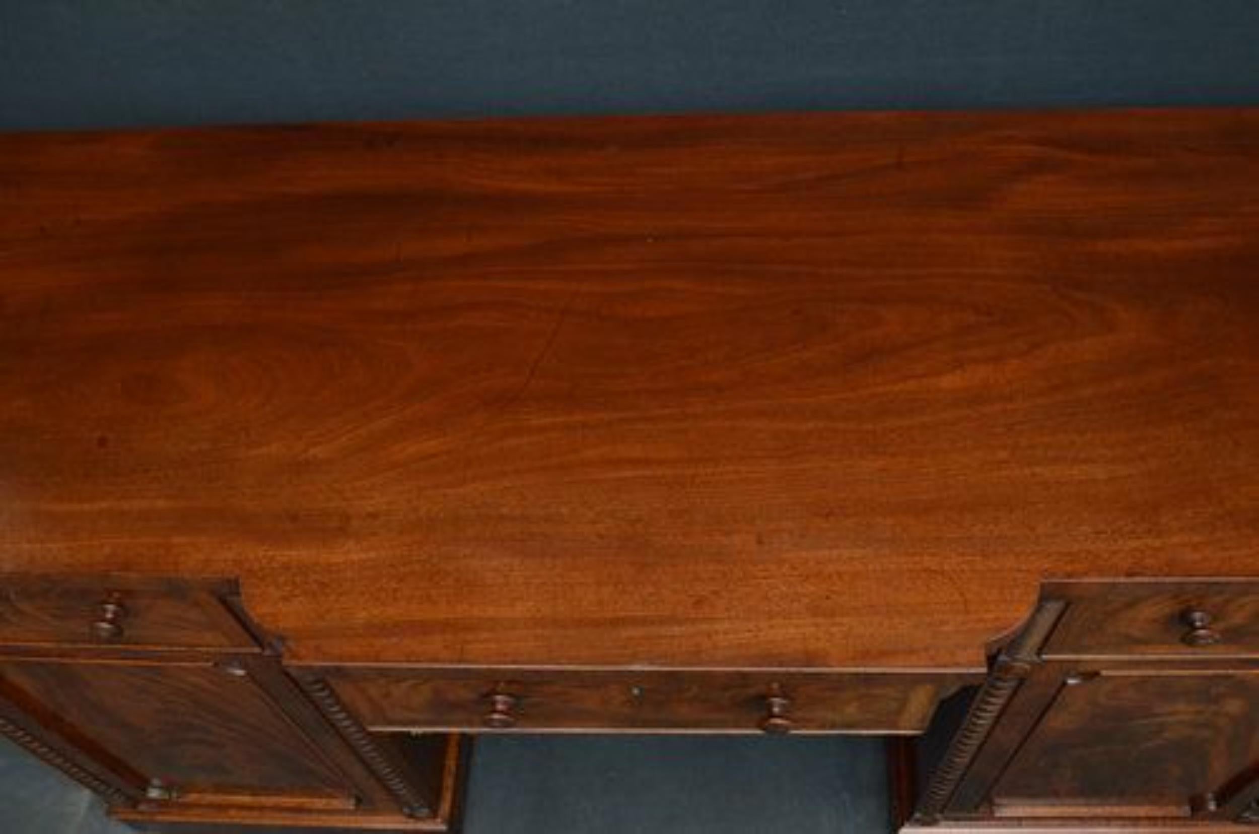 Sn033 Fine and unusual Regency, mahogany, breakfronted, pedestal sideboard, having figured top above frieze drawer with carved apron below, all flanked by full length, panelled, flamed mahogany cupboard door, all fitted with original turned knobs