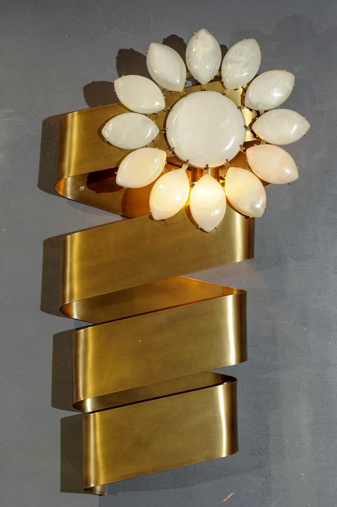This original wall lights is made of brass, with an alabaster flower. Each sconces wears a light bulb. A pair is available.