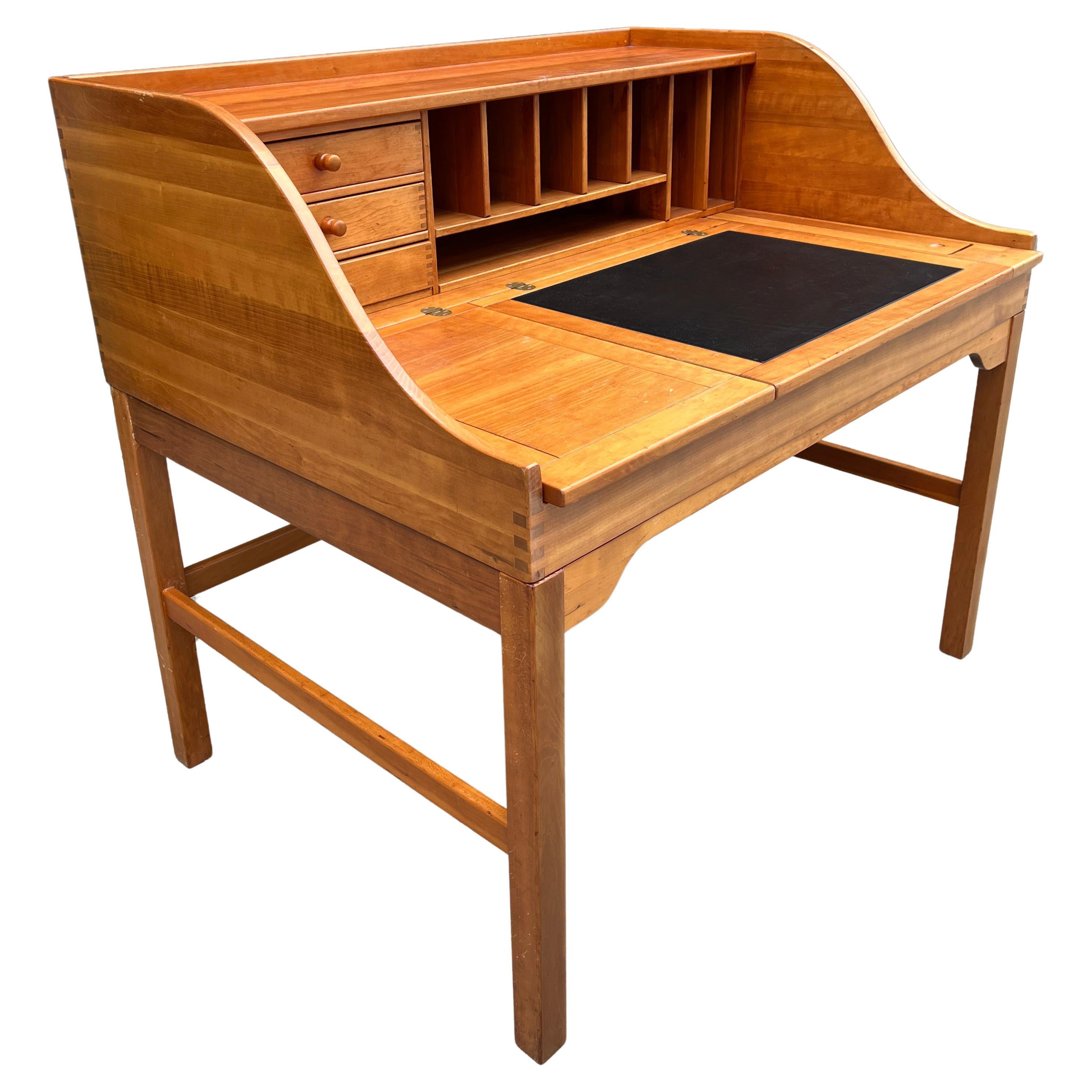 A Mid-Century Modern free-standing desk made Cherry with a likeness of teak wood, designed by Andreas Hansen. Featuring large top with three compartments. Two with flip top leaves, and under storage compartments, middle section with a black leather