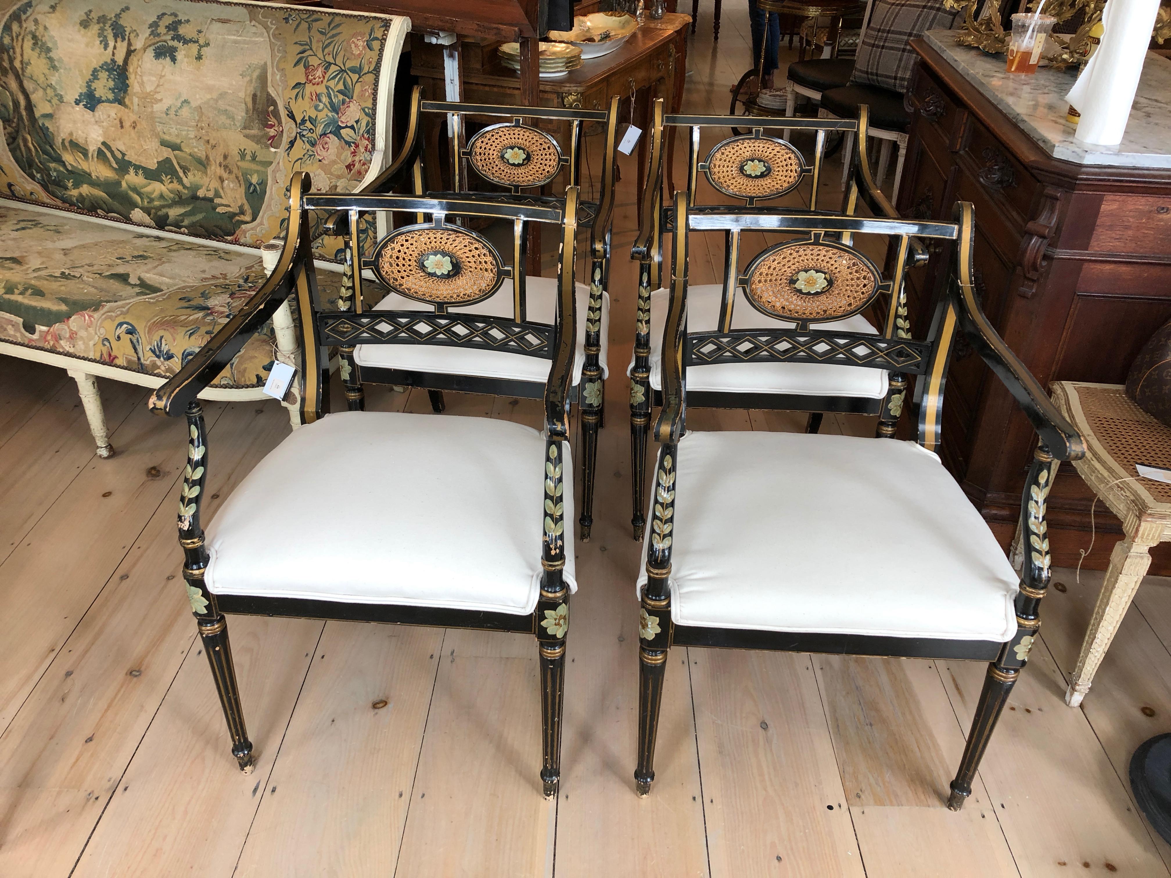 Elegant and glamorous set of four Regency armchairs having black laquered background with lovely handpainted foliage in sage green and gold. The backs have spectacular oval caned medallions with sage green and gold flowers in the center. Newly