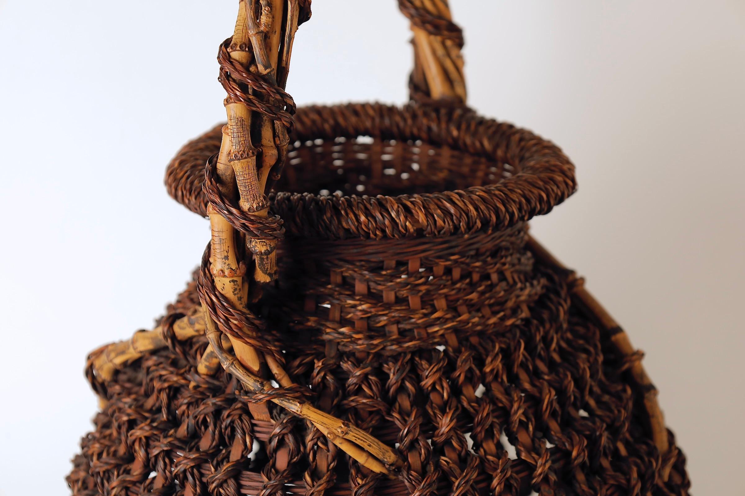 Un cesto di bambù Ikebana giapponese splendidamente realizzato e firmato, che mette in mostra l'eleganza e la raffinatezza della cesteria tradizionale giapponese.
La forma ampia e arrotondata è graziosamente bilanciata da un manico alto, creando un