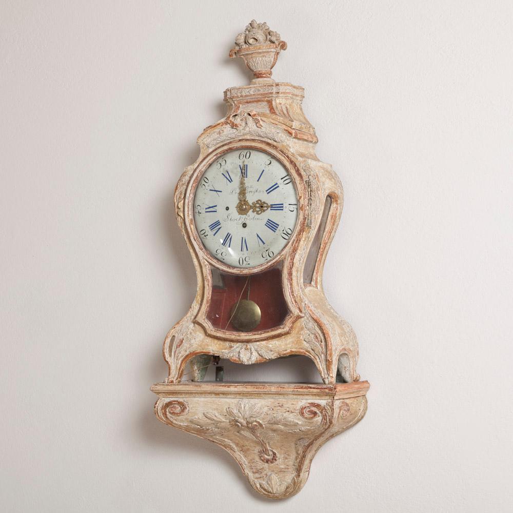 A Superb Swedish Rococo cartel clock complete with bracket and in original paint and traces of gilding. The cartouche shaped frame is carved with foliage and surrounds the glassware to the front and sides housing the pendulum. The clock is topped