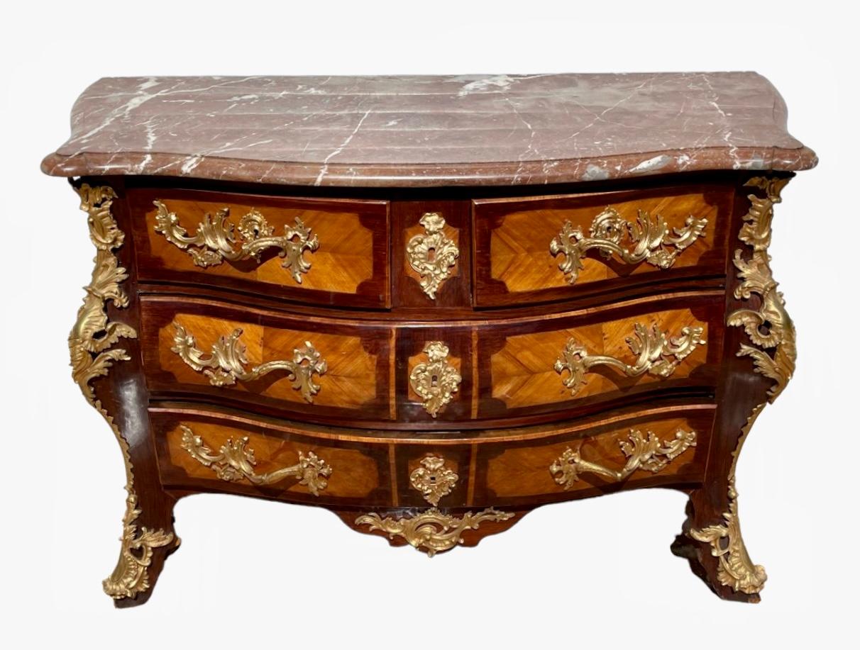 Superb tomb chest of drawers in rosewood and rosewood marquetry in Regency style. It opens with 4 drawers and is richly decorated with chiseled gilded bronzes. It has an original marble top and is in good condition. It is in very good state of