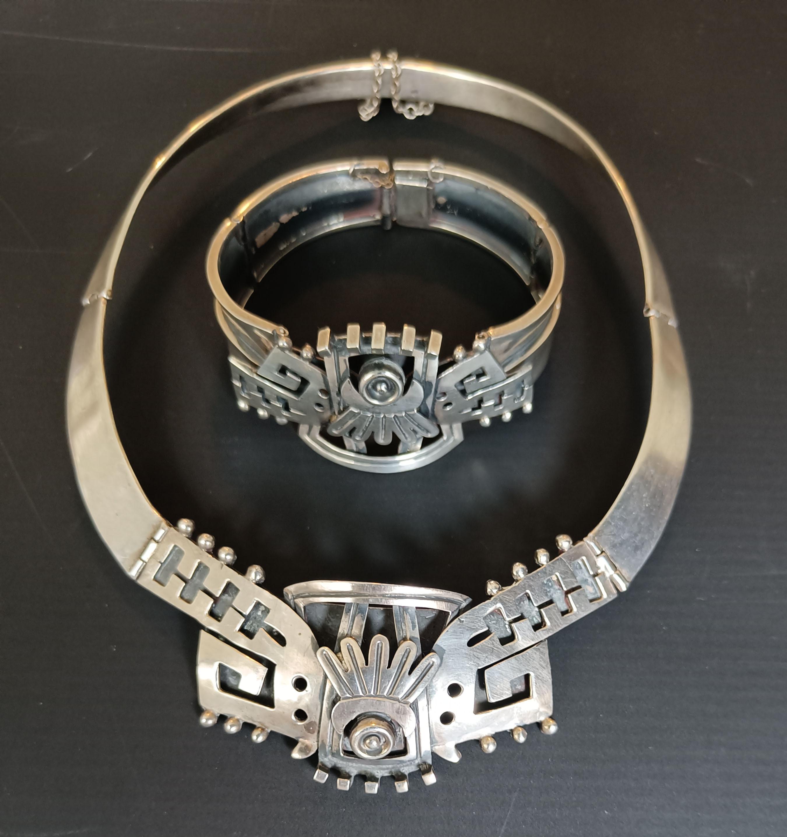  

Uno splendido e da collezione girocollo e bracciale d'argento vintage di VOO, realizzato a Taxco Mexico e risalente agli anni Settanta. Questo splendido pezzo in argento massiccio è caratterizzato da una tradizionale lavorazione a piume azteche e