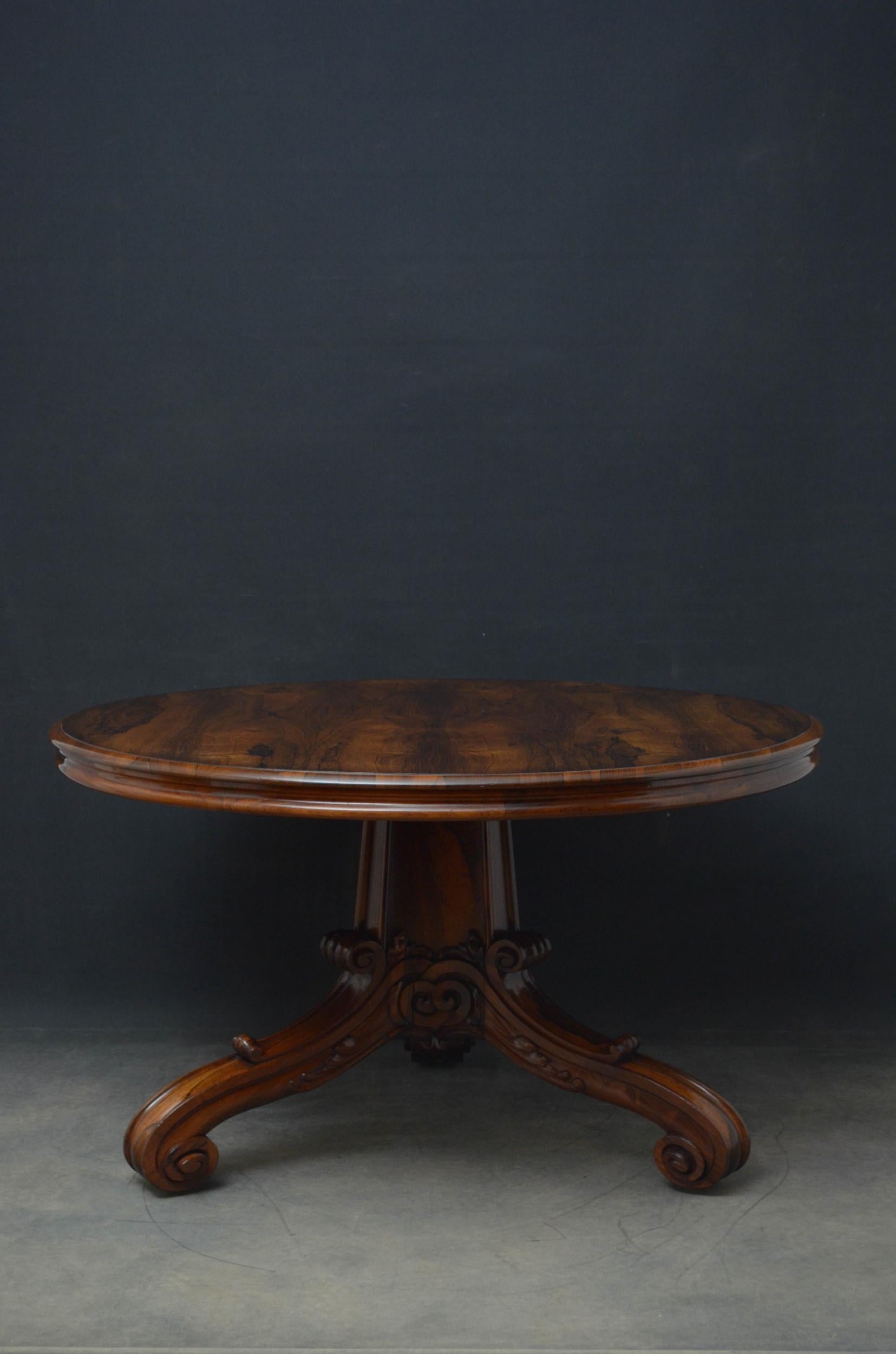 Sn4908, superb William IV, tilt-top center table in rosewood, having very attractive grain to the top above shallow and shaped frieze, raised on substantial three-sided carved column terminating in three scrolled and leaf carved legs, all standing