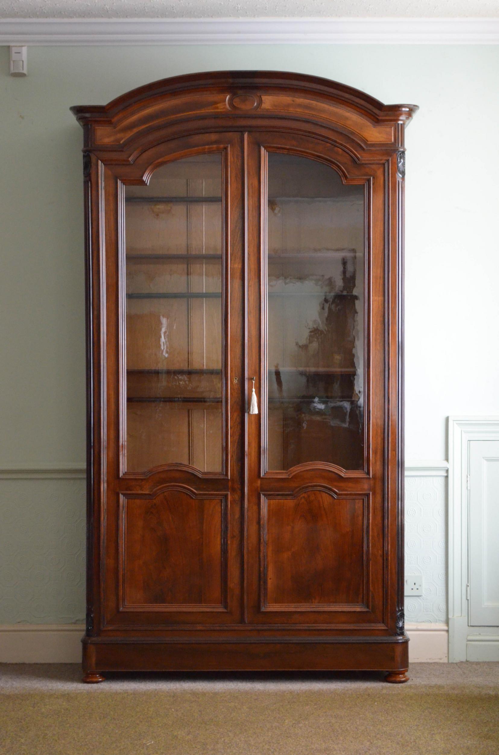 Sn5100 elegant and very capacious 19th century display cabinet or bookcase in rosewood, having arched top with fielded frieze above a pair of glazed doors retaining its original glass, fitted with original working lock and a key and moulded panels