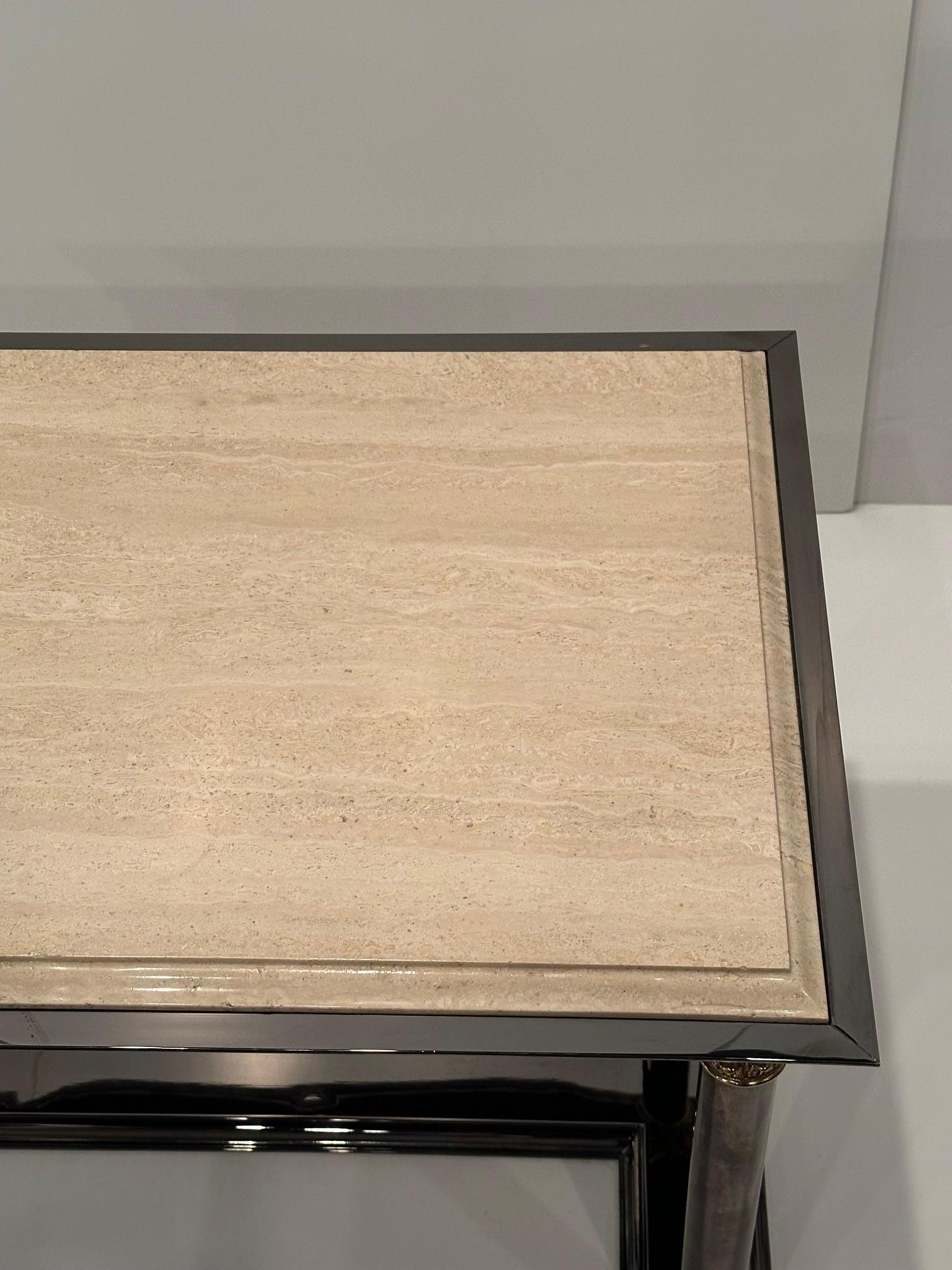 Impresionante y elegante mesa de cóctel con una estética neoclásica y una elegante mezcla de columnas de acero teñido de negro con detalles de latón, todo ello compensado con un tablero de mármol crema.  La mezcla de negro, dorado y crema es un