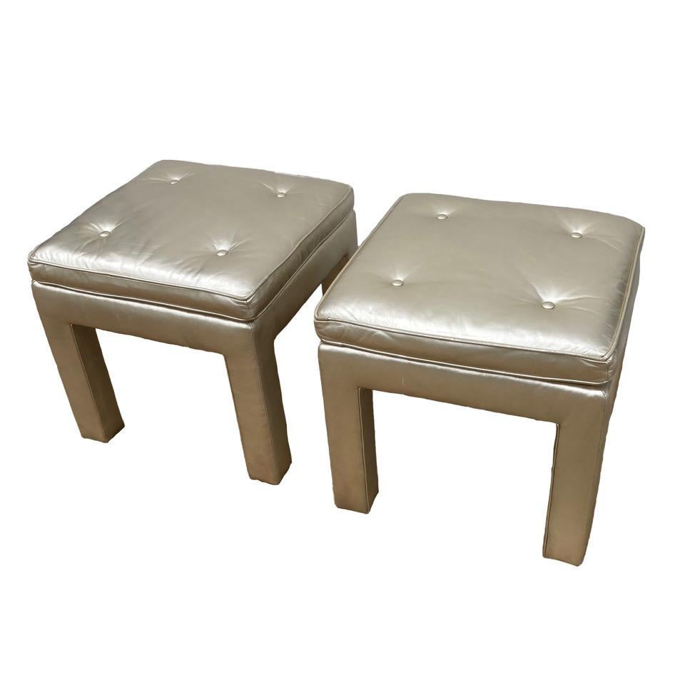 A really fun pair of 80s Parsons-leg stools with chic semi-attached seats, covered in a platinum colored leather. The leather is in very good condition, and it has a medium sheen. A little different, a lot cool. Age appropriate wear. Minor scuffs