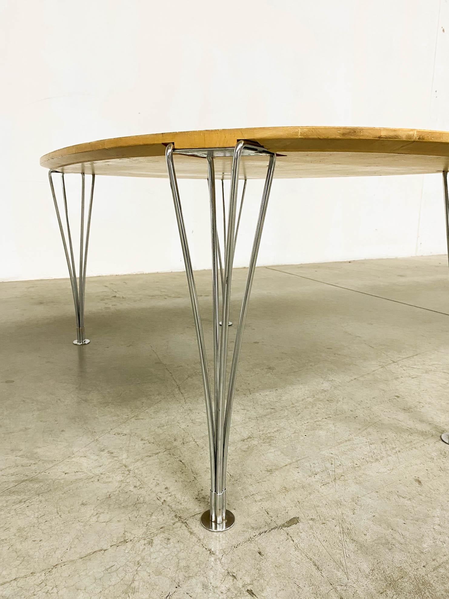 Introducing the collaborative masterpiece by Bruno Mathsson and Piet Hein: the Scandinavian Modern Superelips Dining Table. Manufactured by Fritz Hansen in Denmark, it boasts an attribution mark for authenticity. Crafted with chrome plating, metal,