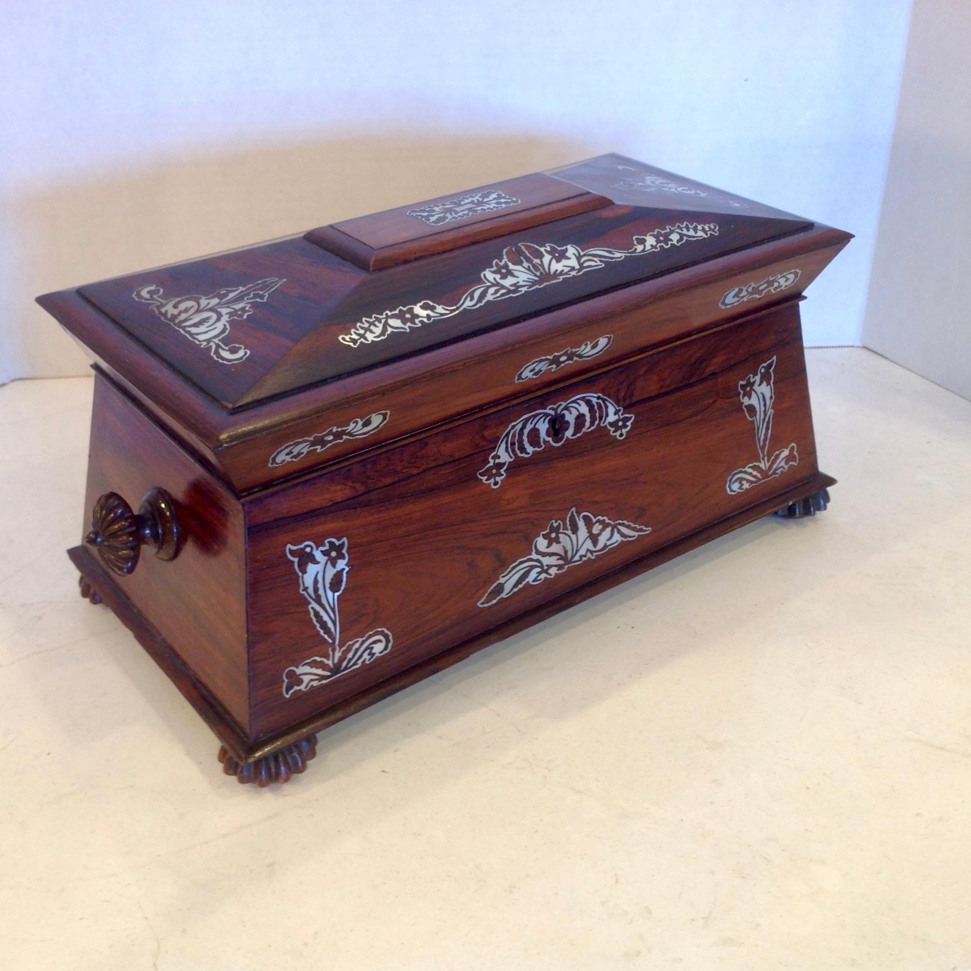 Finely fashioned in rosewood and appointed with elaborate mother of pearl inlays .
It is raised upon exquisitely carved feet with complementary handles .
It is generously scaled - far larger than most and made for the English market .