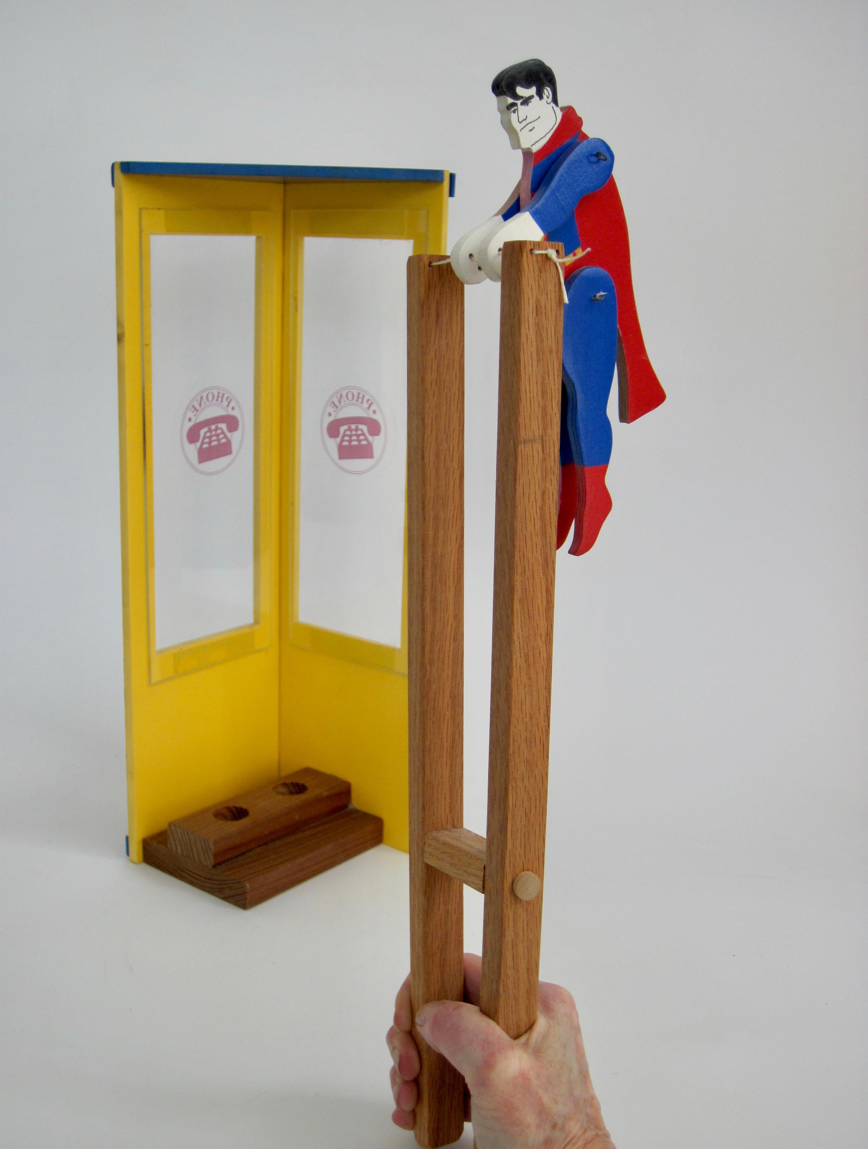 Superhero Superman on one side and Clark Kent on the other, wooden trapeze artist toy with graffiti phone booth holder. Squeeze the ends of this and he flips around.