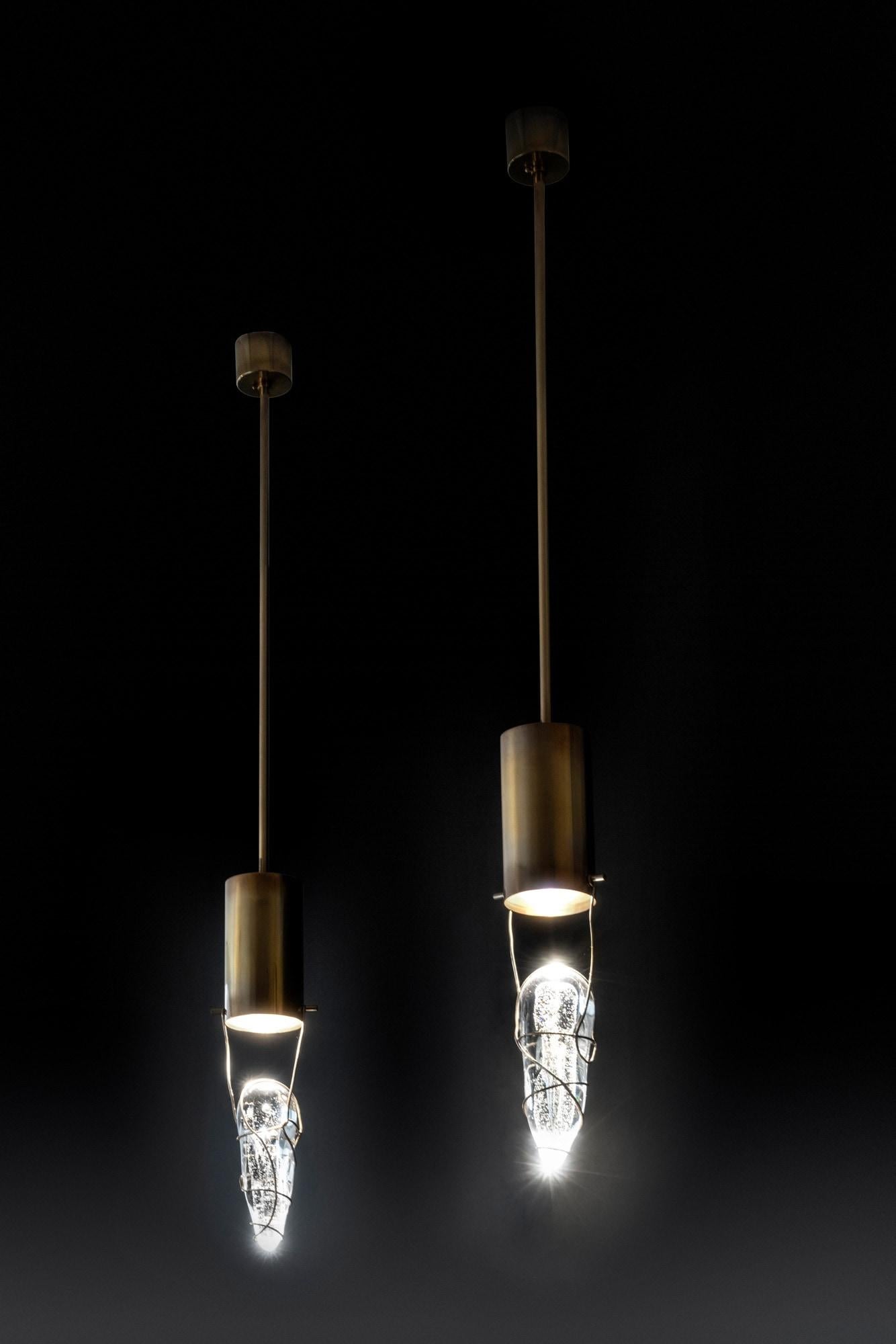 Suspension in slightly burnished brass. The handmade detail, almost suspended, screens and diffuses the light that comes from the light source inside the brass cylinder.
