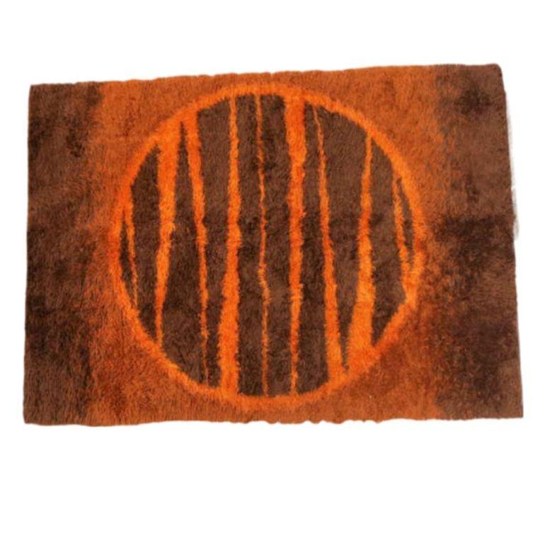 Postmodern shag wool area rug with an abstract design resembling a sun featuring various shades of browns and burnt orange.
An excellent colorful rug to accent your room with color infused textile.