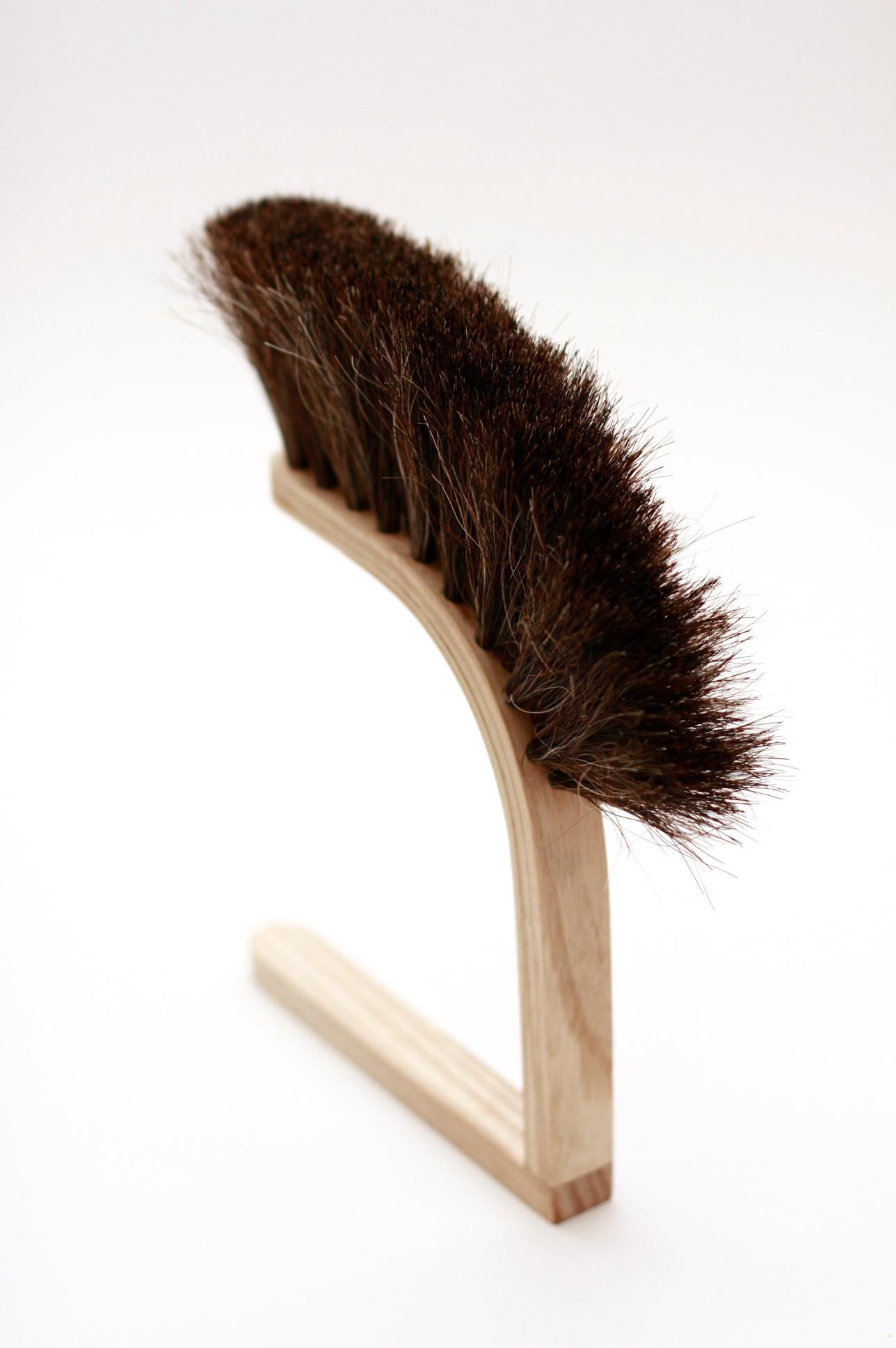 This hand broom is inspired by an old superstition that it's bad luck to rest a broom on its bristles. The unique handle allows it to be hung off a ledge or placed upright on a surface, not just good for good measure, but to keep the bristles