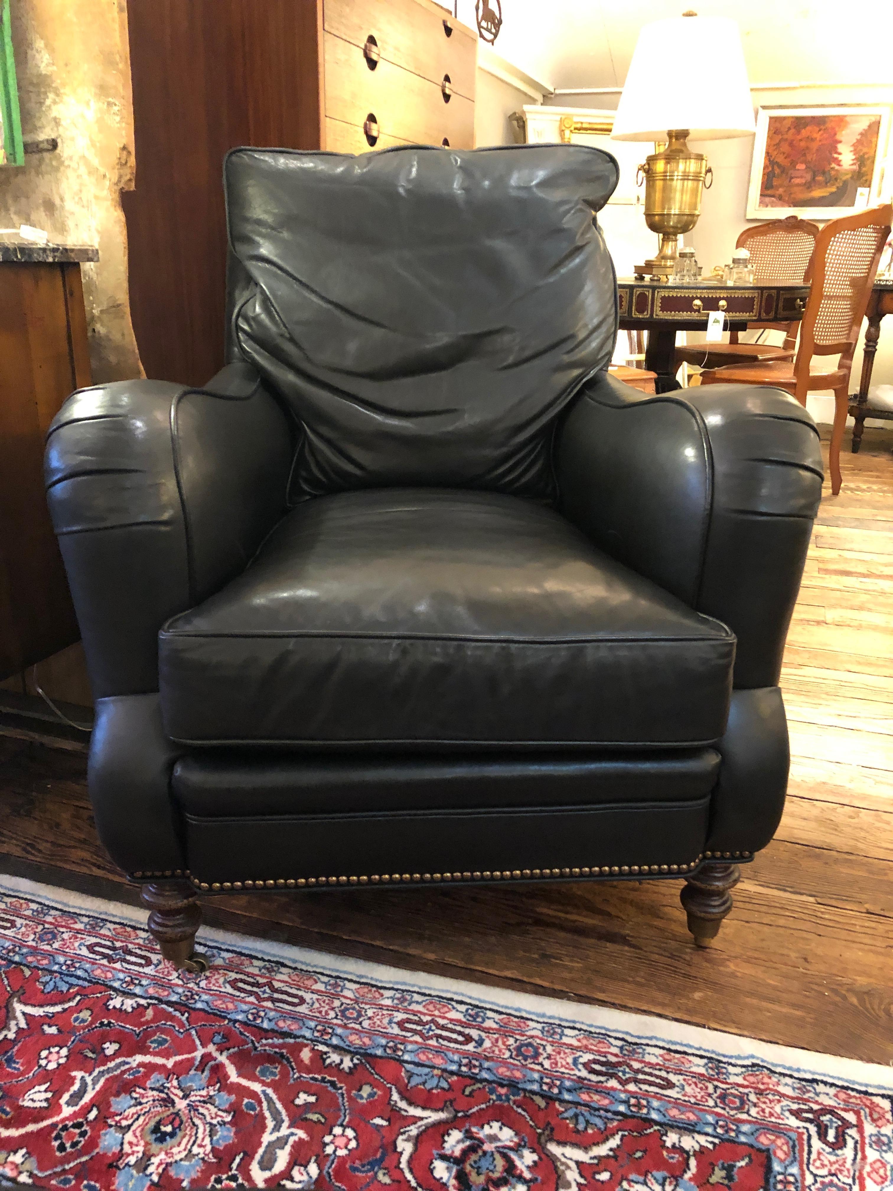 Super comfortable dark charcoal leather club chair and matching ottoman having scroll arms, mahogany turned feet, and handsome brass nailheads. Back cushion is attached; seat is removable.
Label reads Wesley Hall
Seat height 18.75
seat depth