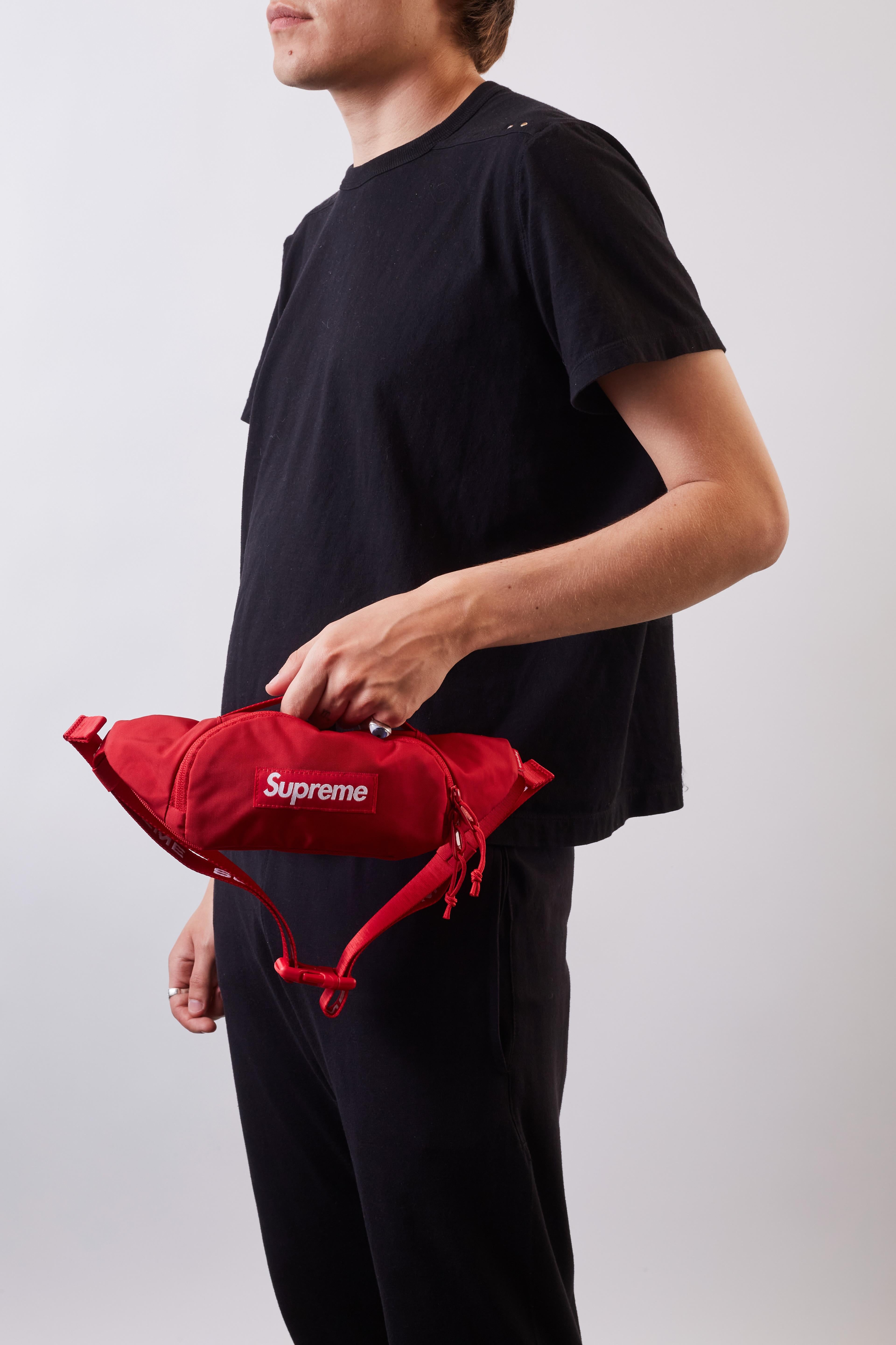 Supreme is back with its iconic streetwear staples for summer. This red-coloured small waist bag has a water-resistant construction divided into two compartments - one with a zipper and the other, on the inside, features a touch strap. A signature
