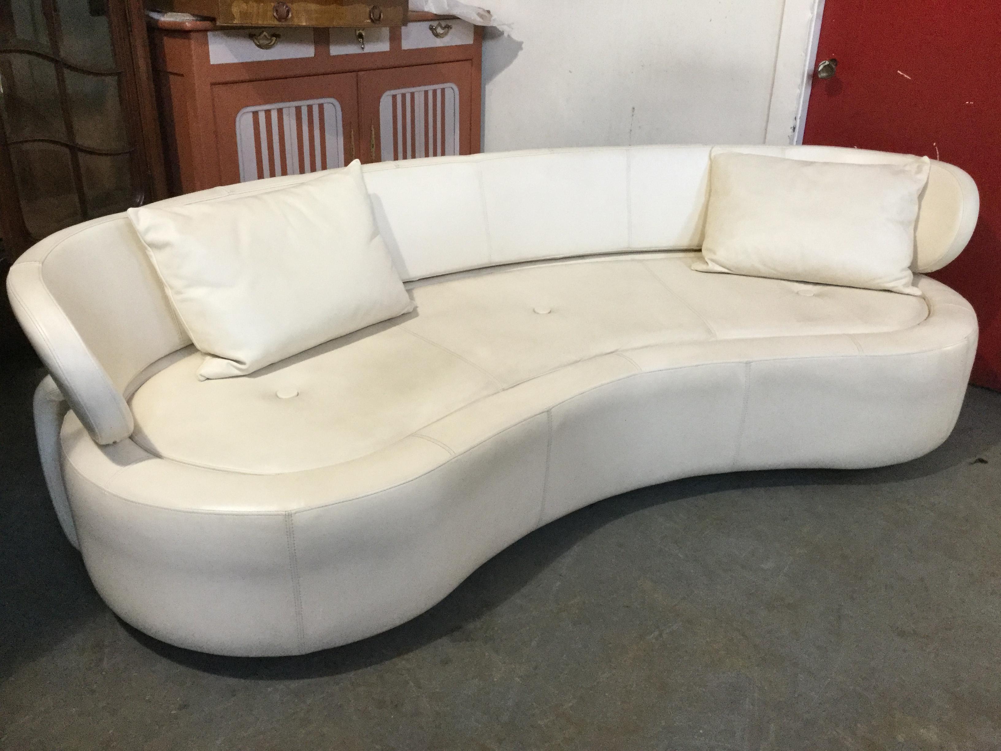 Sleek Danish modern white leather sofa, circa 1980s , having a super sexy sculptural curved silhouette with a long, low-slung back. There is detailed stitching and unusual leather panels attached to back for a haute-couture look. Two throw pillows
