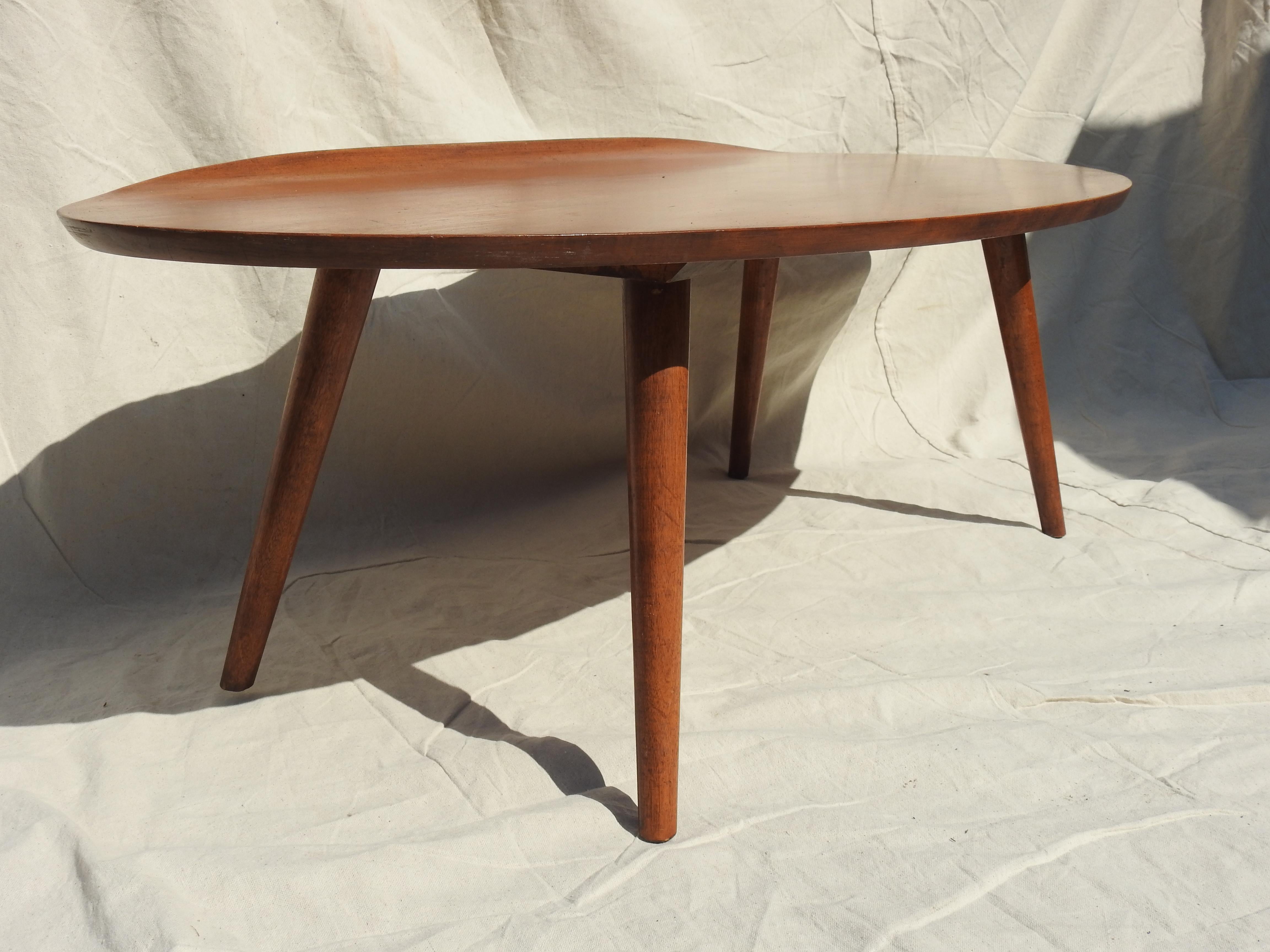 Gorgeous midcentury 1950s Russell Wright designed surfboard coffee or cocktail table with curved lip on one side. Beautiful warm toned walnut surfboard shape sitting on 4 tapered turned legs. Russell Wright Conant ball markings are on underside of