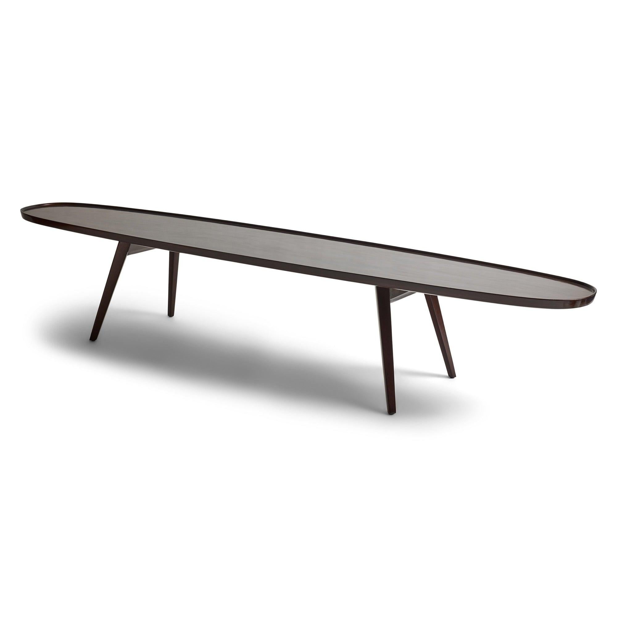 Table basse en acajou foncé avec un plateau ovale étroit bordé d'un bassin sur des pieds effilés et évasés.
