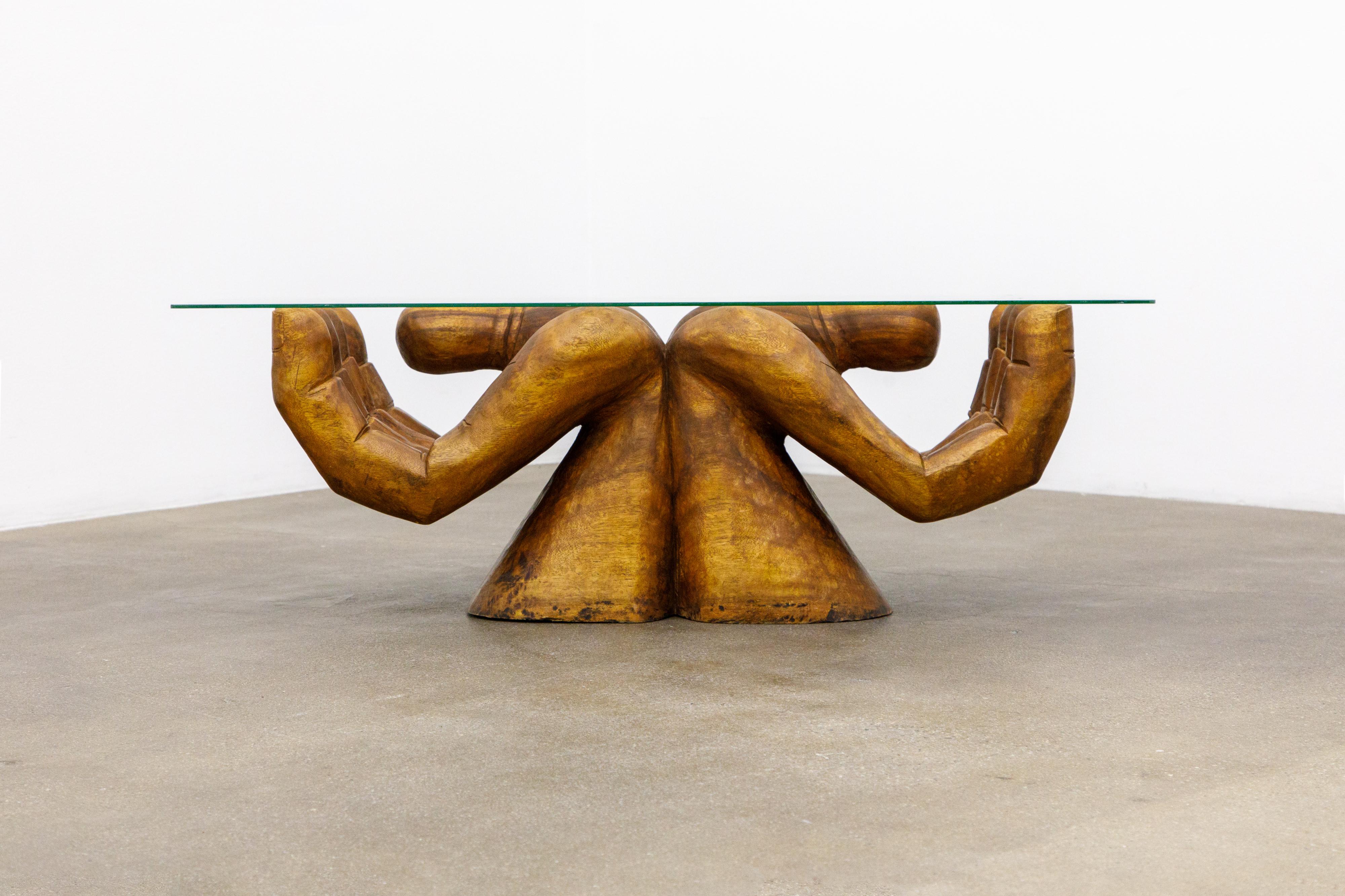 This incredible surreal carved wood coffee table was crafted in circa 1970s in the style of Pedro Pedro Friedeberg. The table features two partially cupped hands which hold the glass top, beautiful subtle details making the hands look real - such as