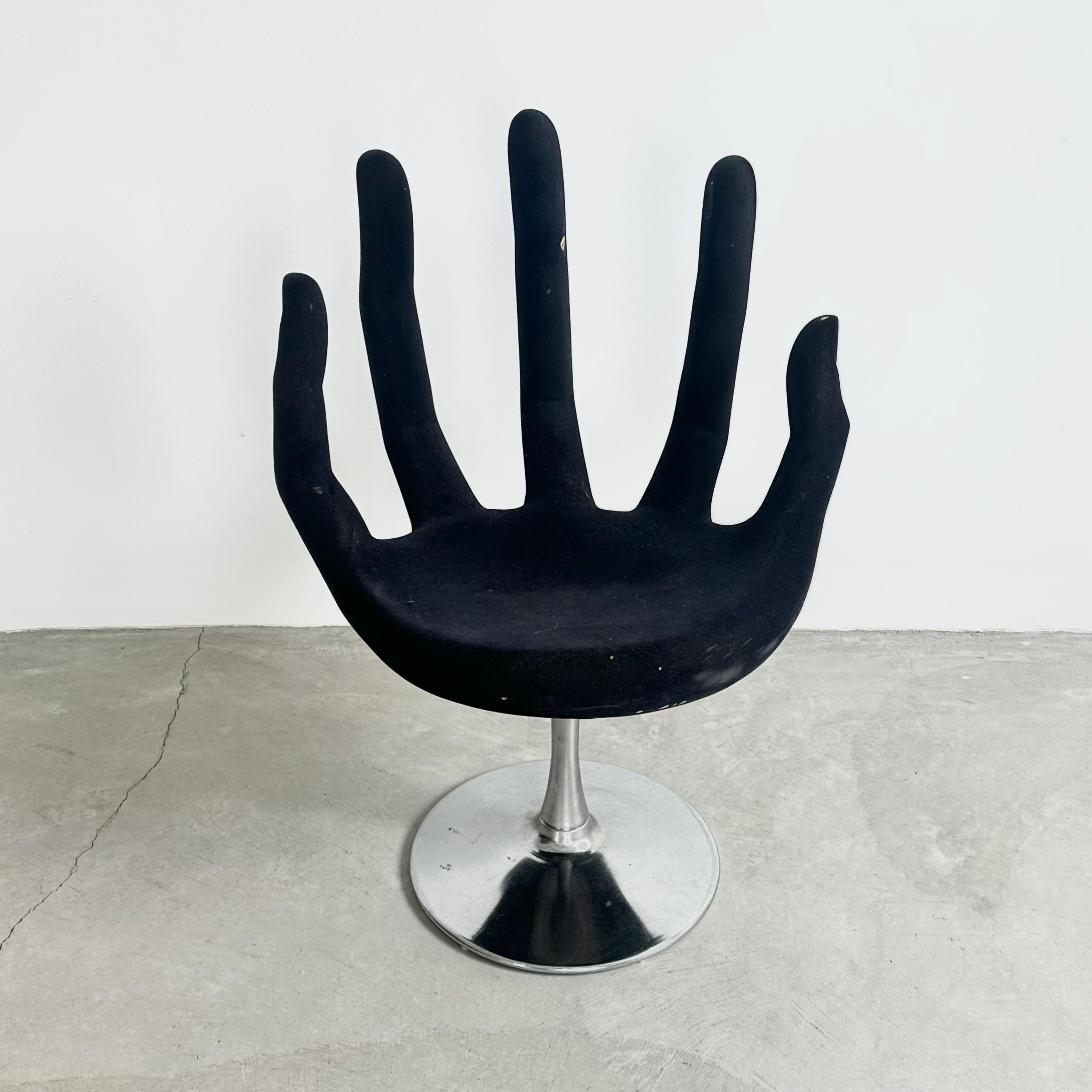 A wonderfully unique and surrealist hand-shaped chair handmade in the 1970s.

Elongated fingers covered in black velvet form the back of the chair, encapsulating the sitter within their slender grasp. The chair rises on a circular chrome base. There