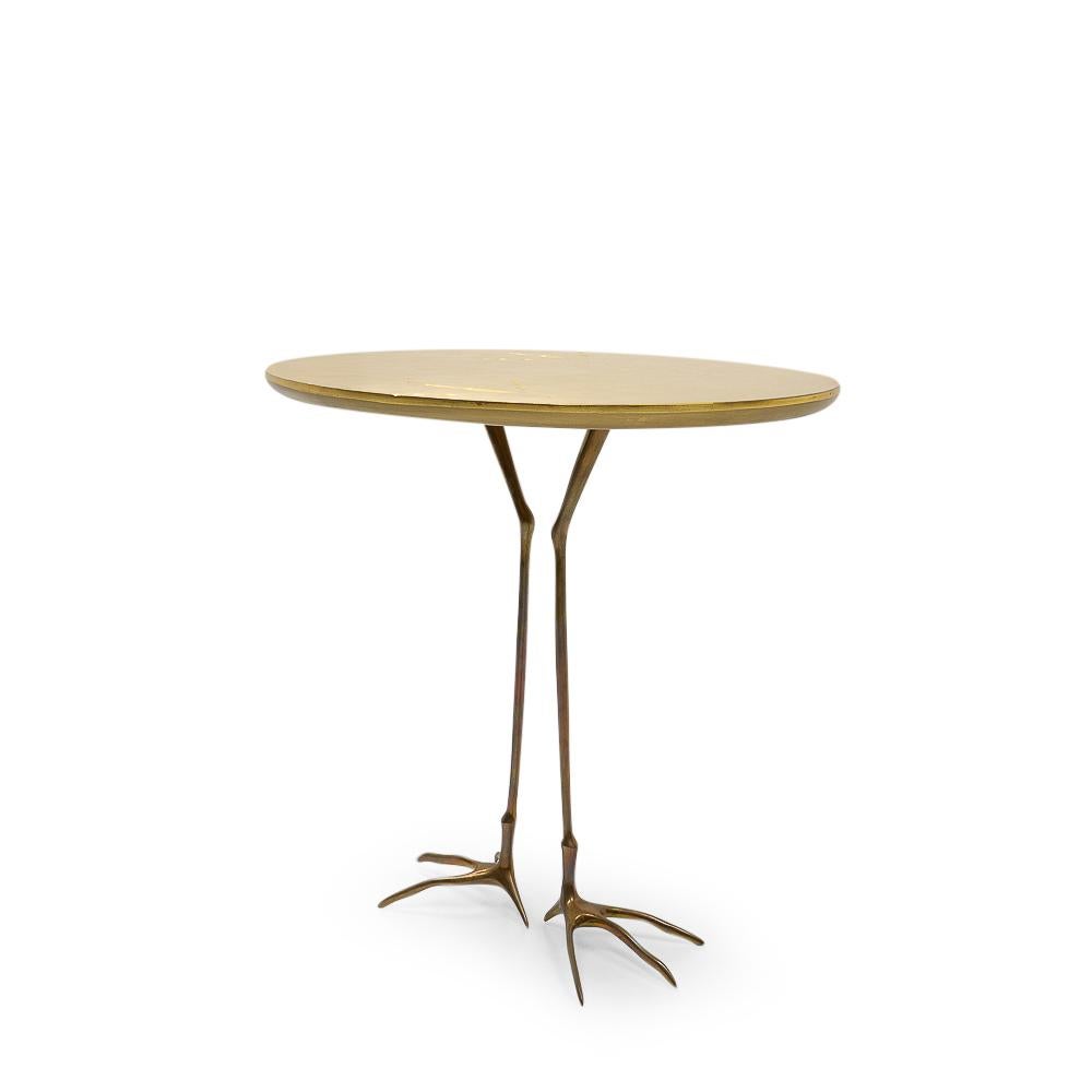 The Traccia (“Trace”) side or coffee table was designed by artist Méret Oppenheim in 1939, representing a birdlike animal. The foot-printed, gold-leaf covered table top is in the shape of an egg, the solid cast bronze legs are those of a bird with