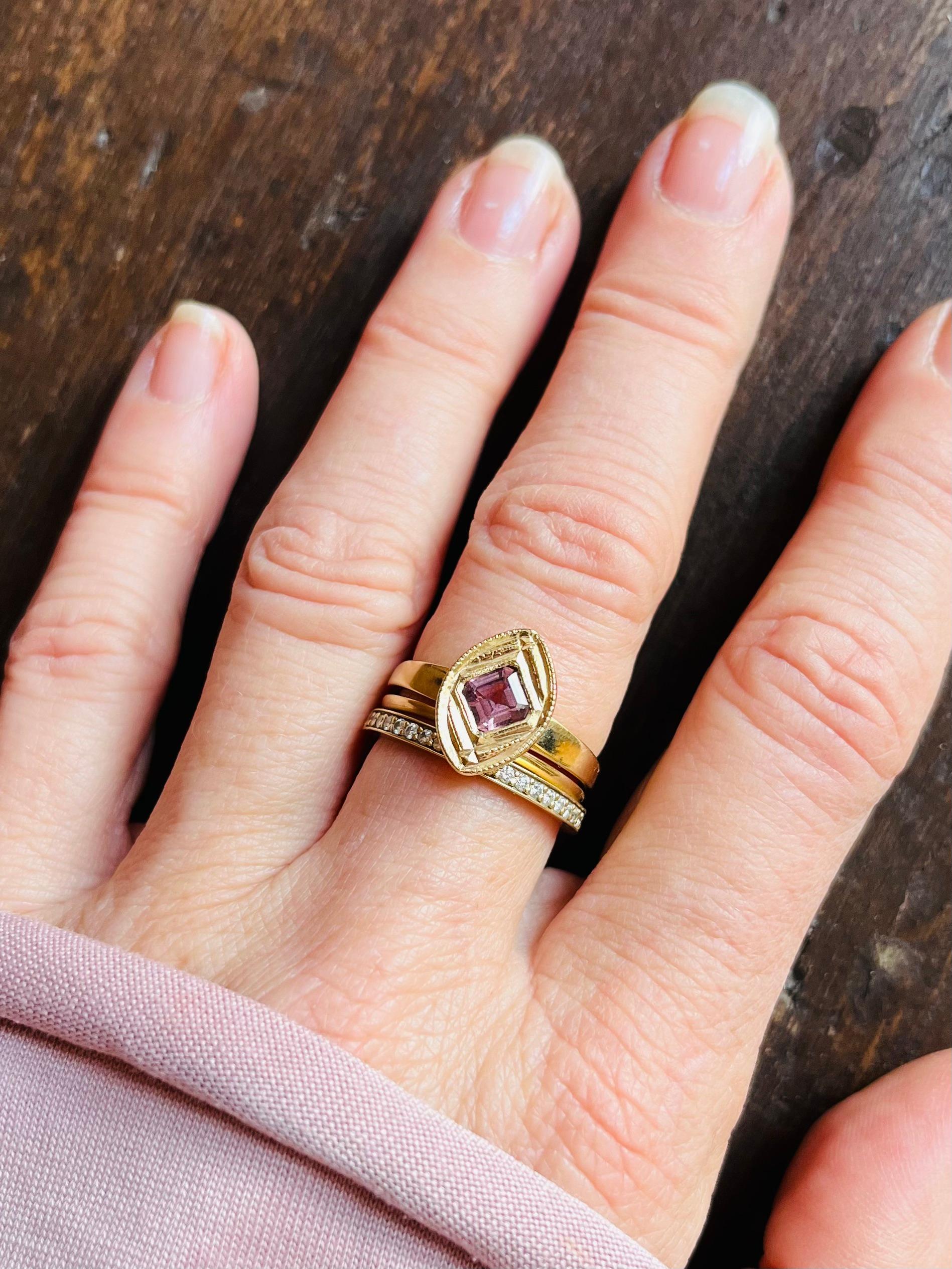 Das Design dieses saftigen, champagner- und himbeerfarbenen Rings aus 14-karätigem Gelbgold mit Rhodolith-Granat im Asscher-Schliff wurde von Himbeeren inspiriert, die unter Brombeeren wachsen.   

Der handgeschnitzte und aus recyceltem 14-karätigem