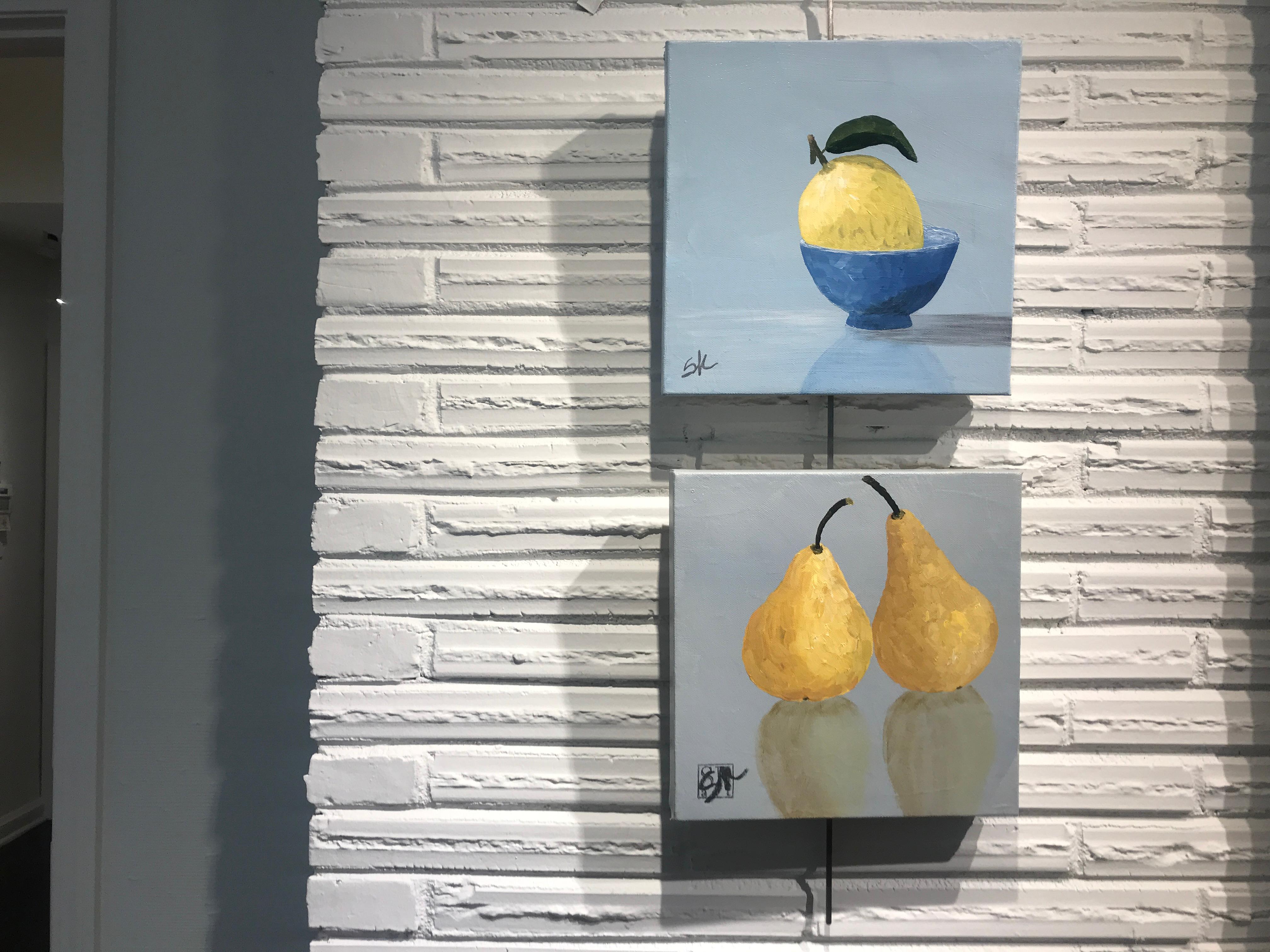 'Lemon in Blue' is a small contemporary still-life acrylic on canvas painting created by American artist Susan Kinsella in 2018. Featuring a lovely palette made of yellow, blue and dark green standing out beautifully on a blue grey background, the