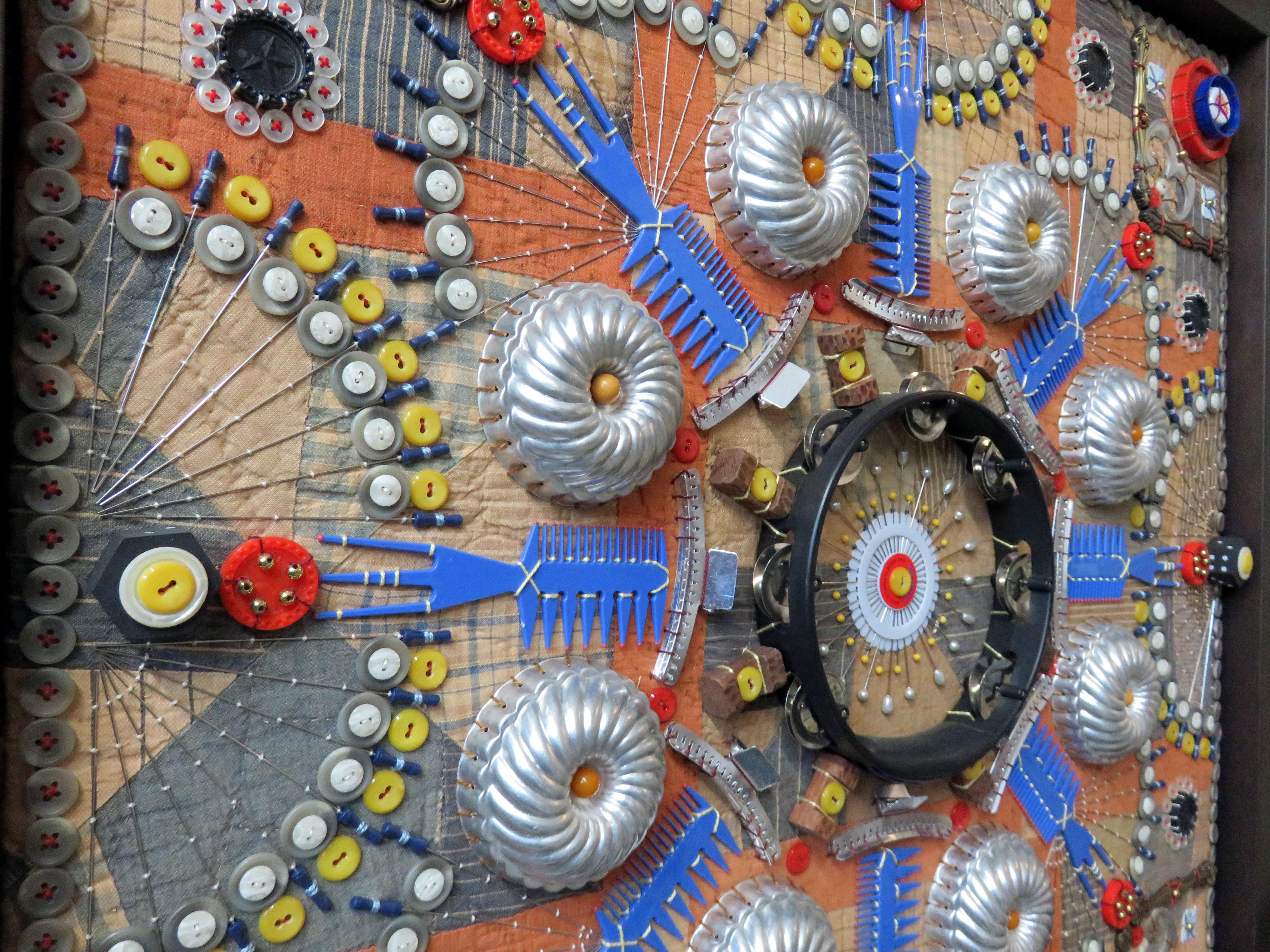This work features hues of orange, yellow, blue and red.

Columbia, South Carolina-based artist, Susan Lenz uses needle and thread for self-expression. Her ongoing series Found Object Mandalas speaks to the universal desire for a place of belonging