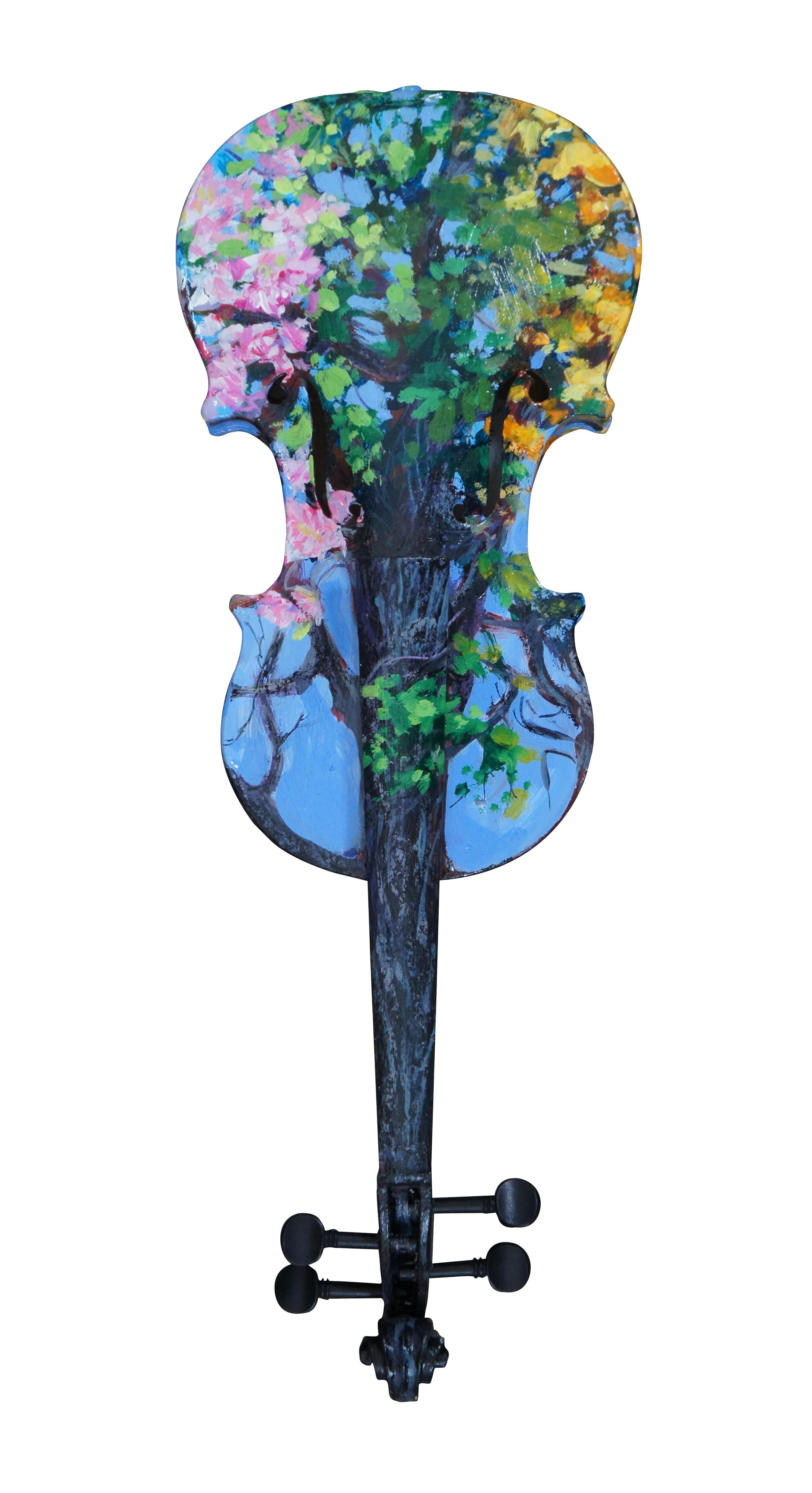 Three dimensional sculpture / mobile artwork by Susan Lucas titled “Four Seasons.” All sides of a re-purposed violin act as the canvas for an Impressionist style tree as it passes through the four seasons – the pink blossoms of spring, the deep