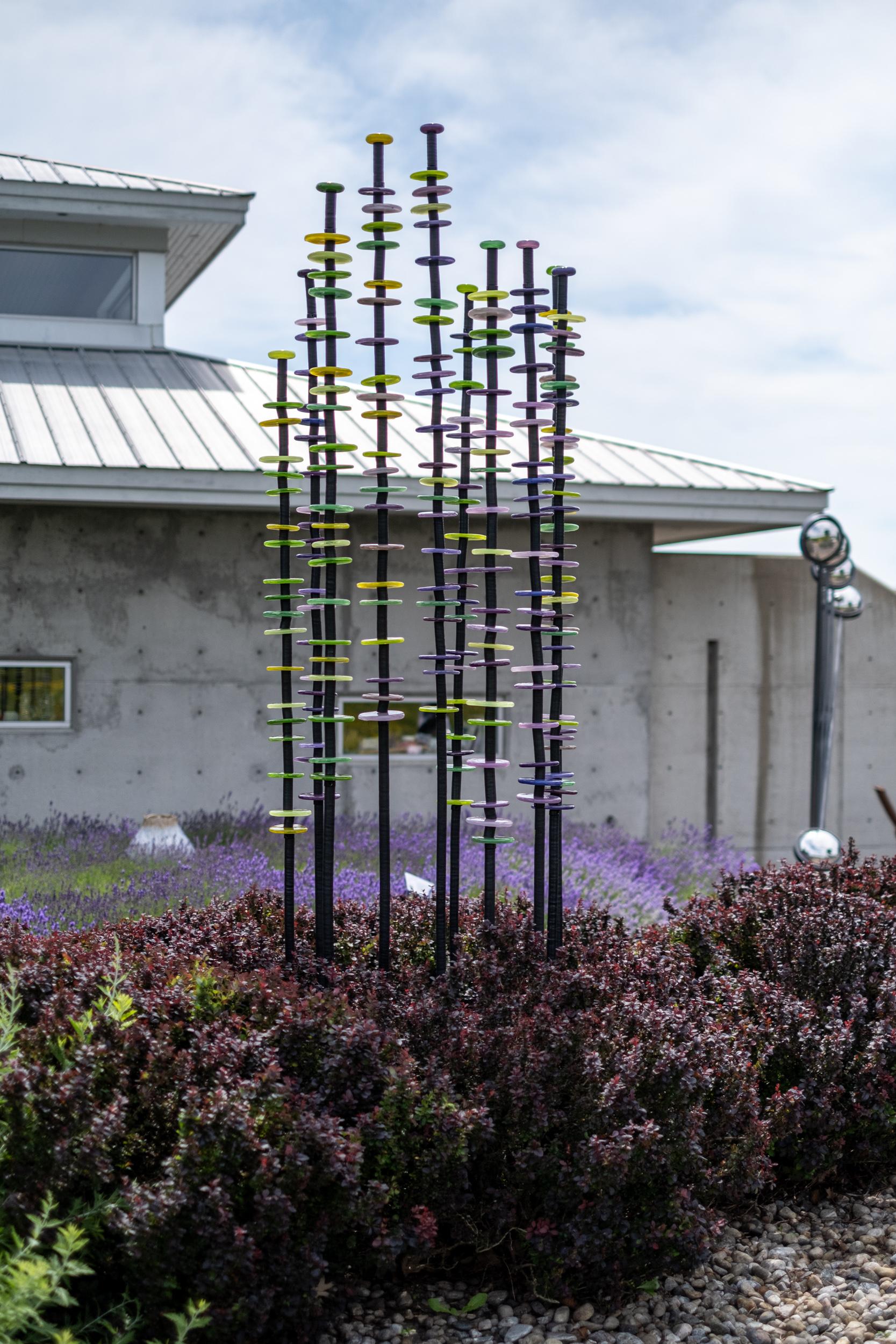 Esta alta y colorida escultura de exterior de vidrio soplado y acero es obra de Susan Rankin. El elegante y colorido arte en vidrio soplado a mano de Susan Rankin se ha expuesto por toda Norteamérica en muchos lugares prestigiosos. Su serie de
