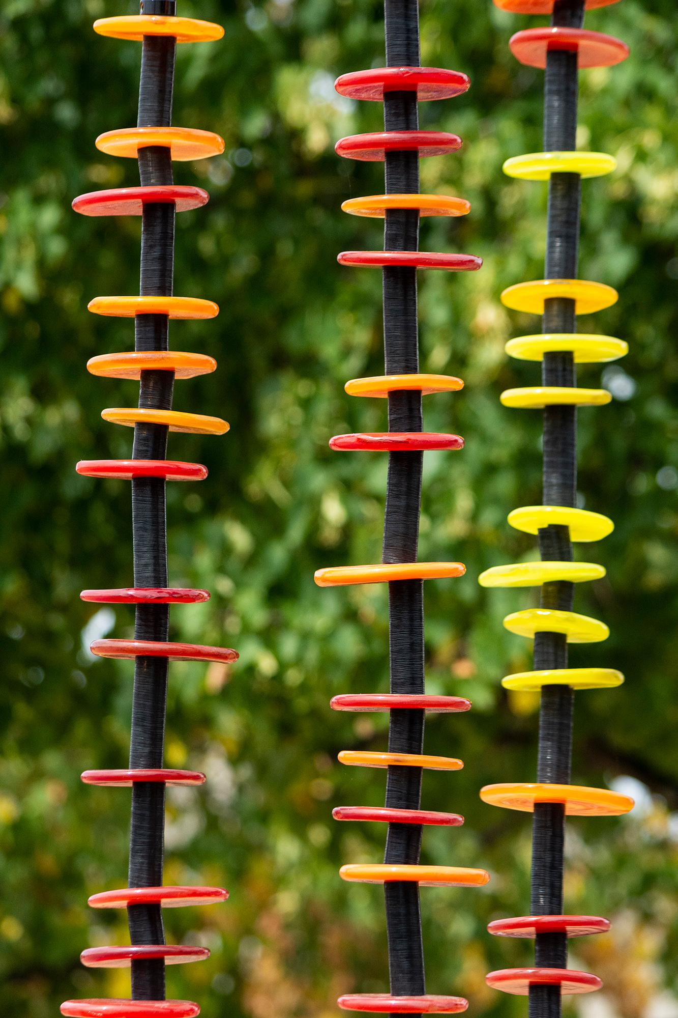 Diese zeitgenössische Glasskulptur für den Außenbereich wurde von der Natur inspiriert.

Die Schönheit der mundgeblasenen Glasringe in Rot, Orange und Gelb leuchtet im Sonnenlicht in dieser reizvollen Außenskulptur von Susan Rankin. Wie Blumen in