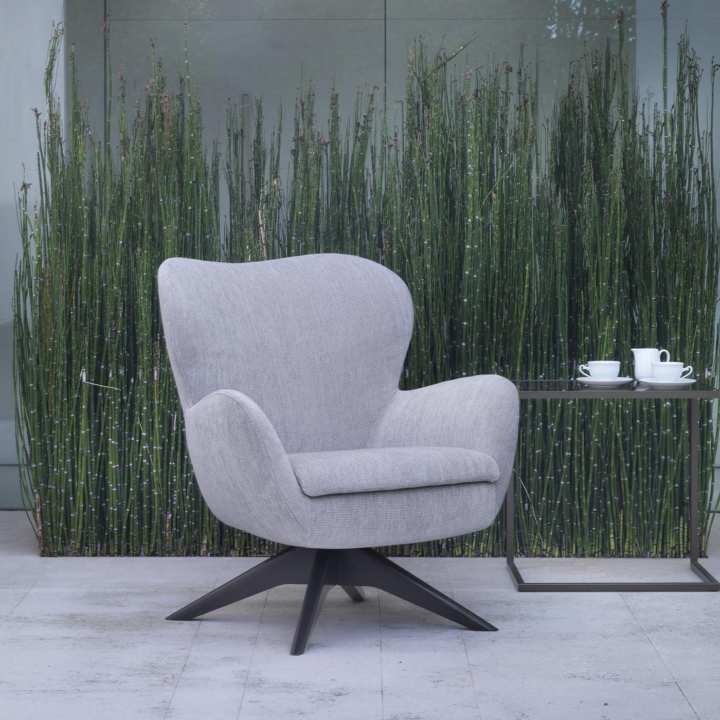 This armchair is defined by soft lines and enveloping shapes. It comes with a standard, fixed base or in a swivel version, both in the choice of wood or chrome. It features a steel body structure, seat with wooden inserts and cold-moulded