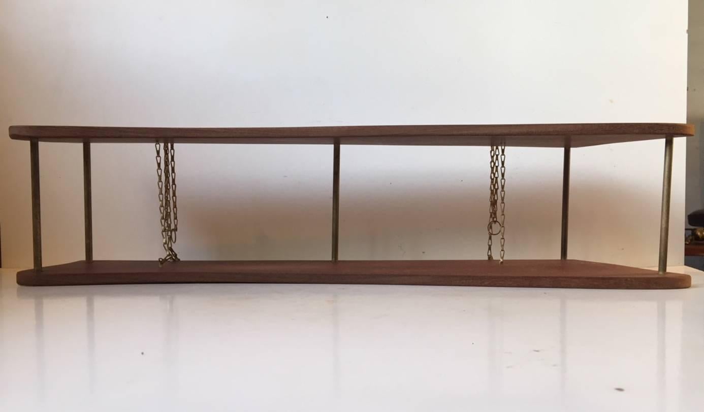 Simplistically constructed teak spice rack or small shelving unit. Organically shaped solid teak profiles assembled with brass tubes and hung/suspended from the wall via the brass chains. Manufactured in Denmark during the 1960s.