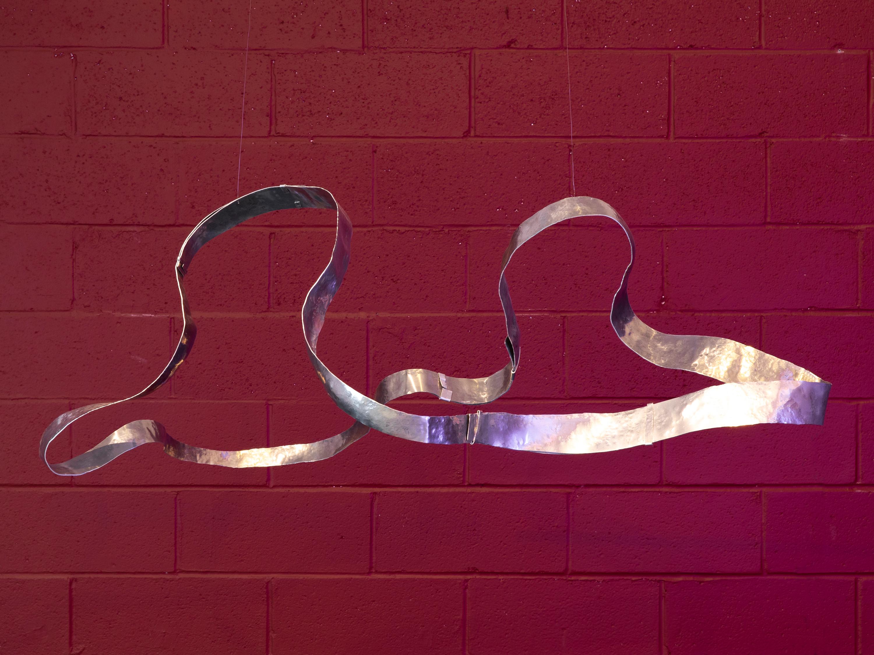 Wave è una scultura sospesa e martellata a mano che si muove delicatamente con l'aria dell'ambiente, coinvolgendo lo spazio circostante in un dialogo tranquillo e continuo. Mentre ruota lentamente, i suoi contorni mutevoli tracciano correnti