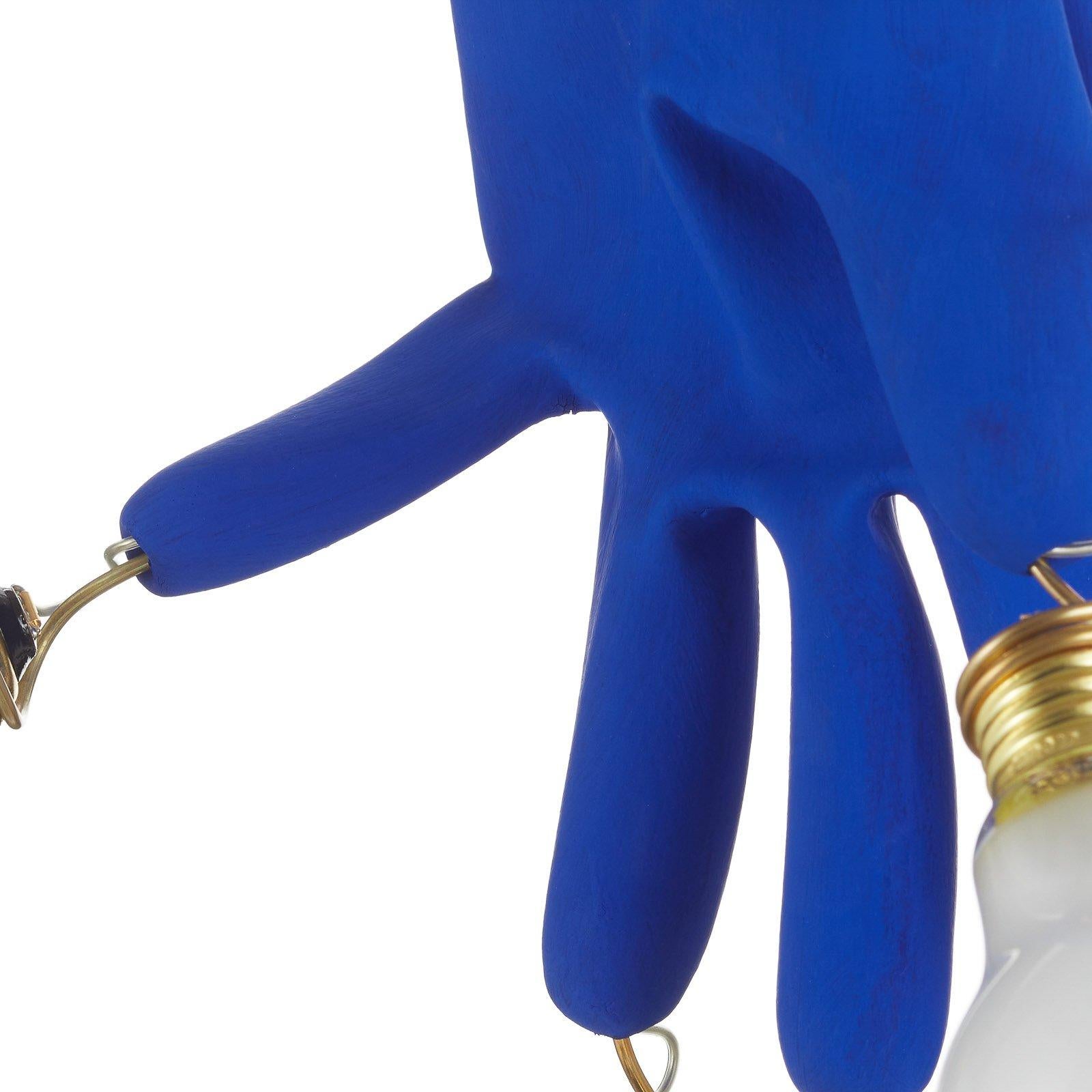 Model No: Luzy Take Five
Diseñador: Ingo Maurer

Luzy Take Five es una lámpara colgante sorprendente y poco convencional que presenta guantes azules con bombillas LED esmeriladas en las puntas de los dedos. Atrevida, controvertida y libre del