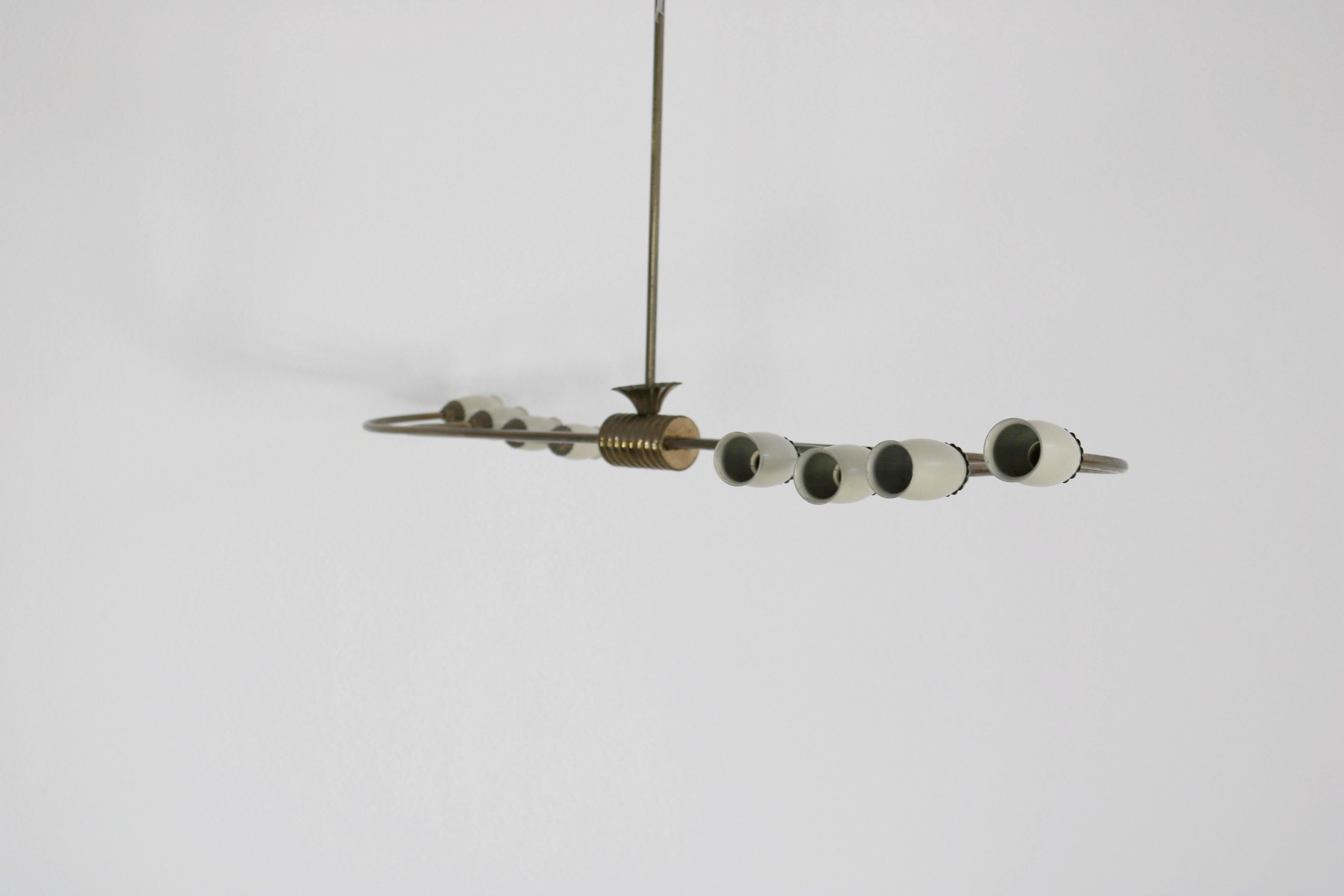 Lampada a sospensione italiana degli anni '50. La lampada stessa è realizzata in ottone e ha 8 piccoli paralumi in alluminio attaccati alle aste ondulate in ottone della lampada. È in condizioni originali e ha una bella patina. La lampada è stata