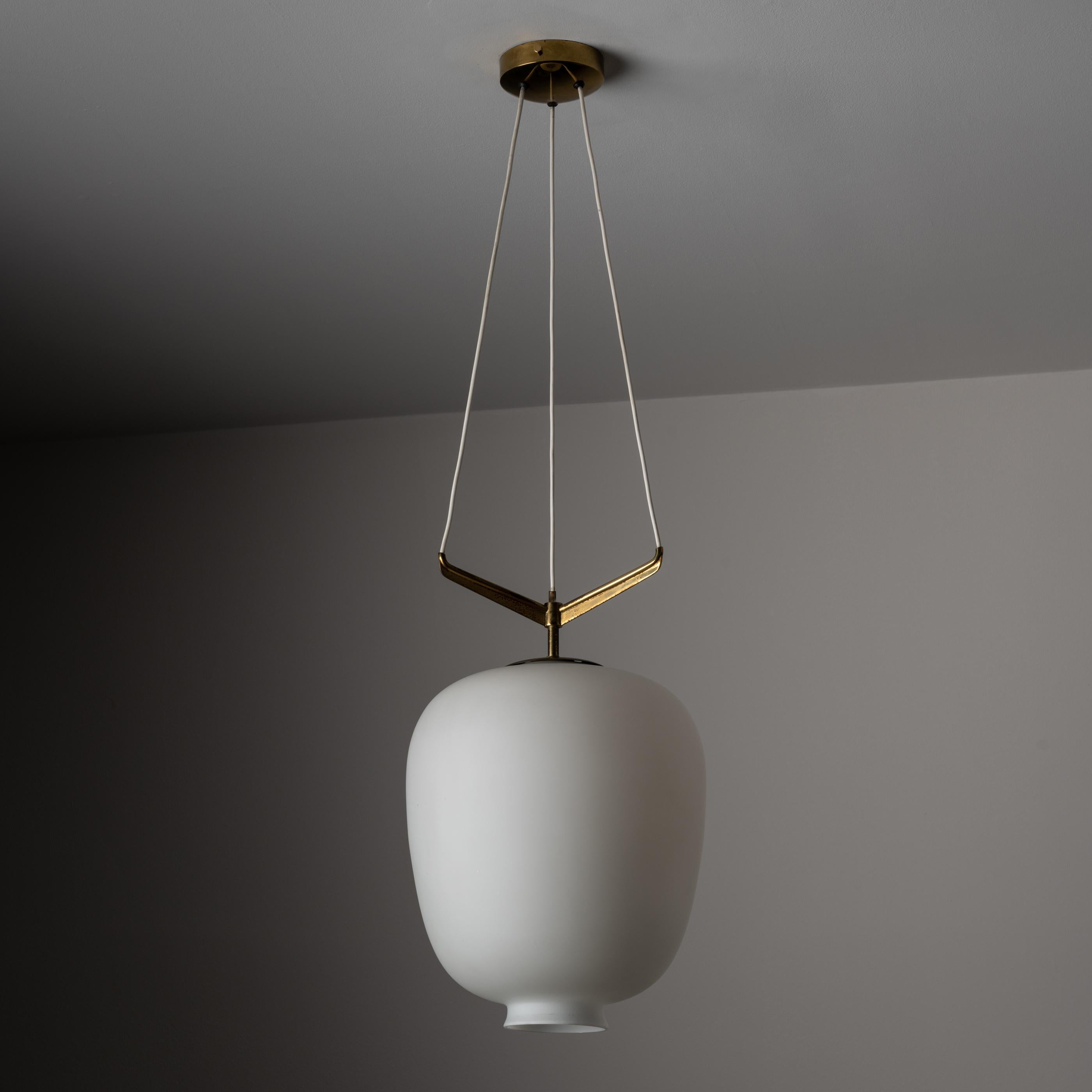 Suspension light by Stilnovo. Manufactured in Italy, circa the 1950s. Features a large frosted glass shade and brass suspension armature. Polished brass arms are naturally aged. Original Stilnovo sticker on base armature. Rewired for U.S. standards.