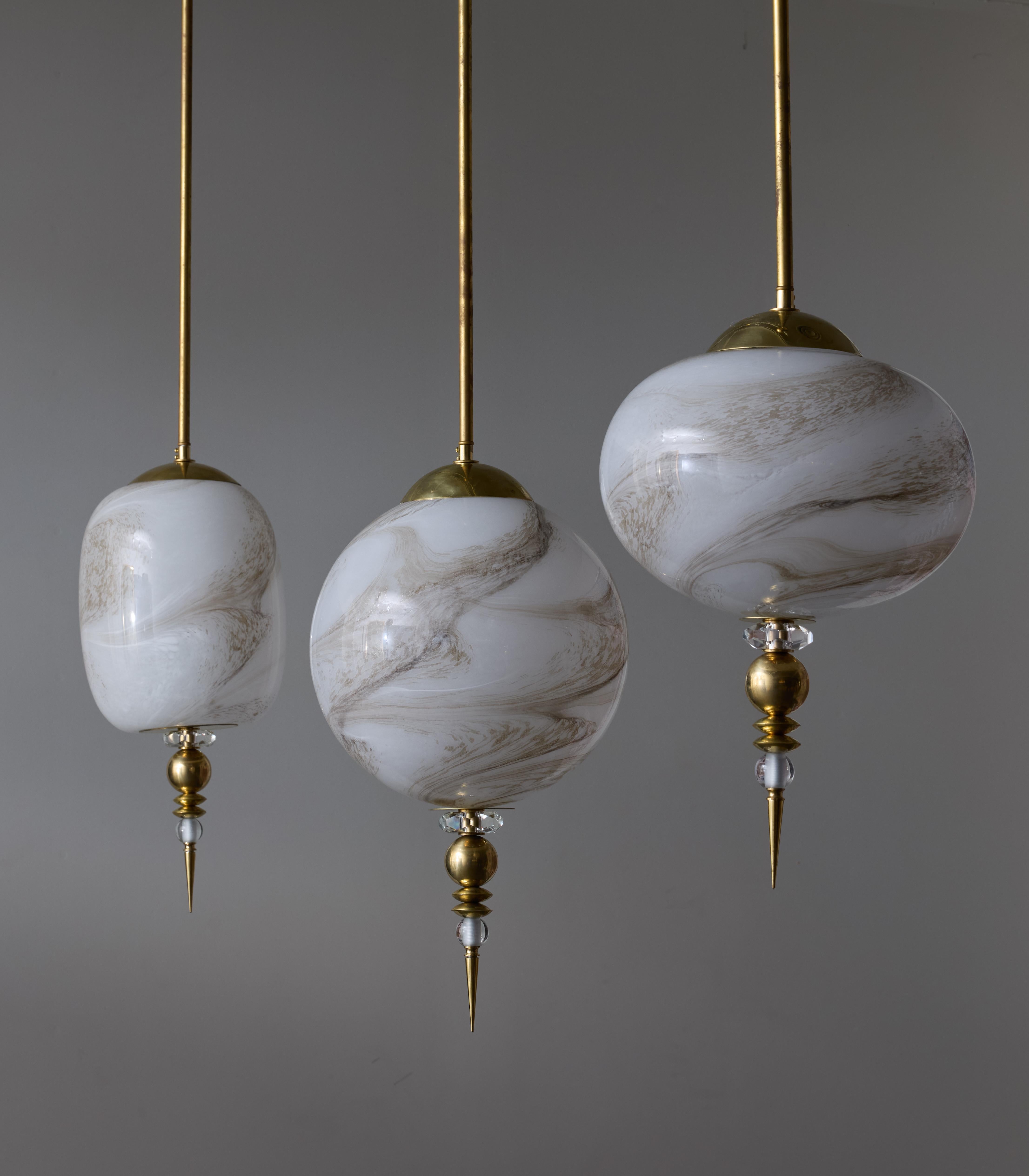 Suspensions made of a brass stem holding a painted glass globe mimicking a natural marbling, and finished with a stack of glass and brass elements.
Two lights per suspensions.

Sold separately