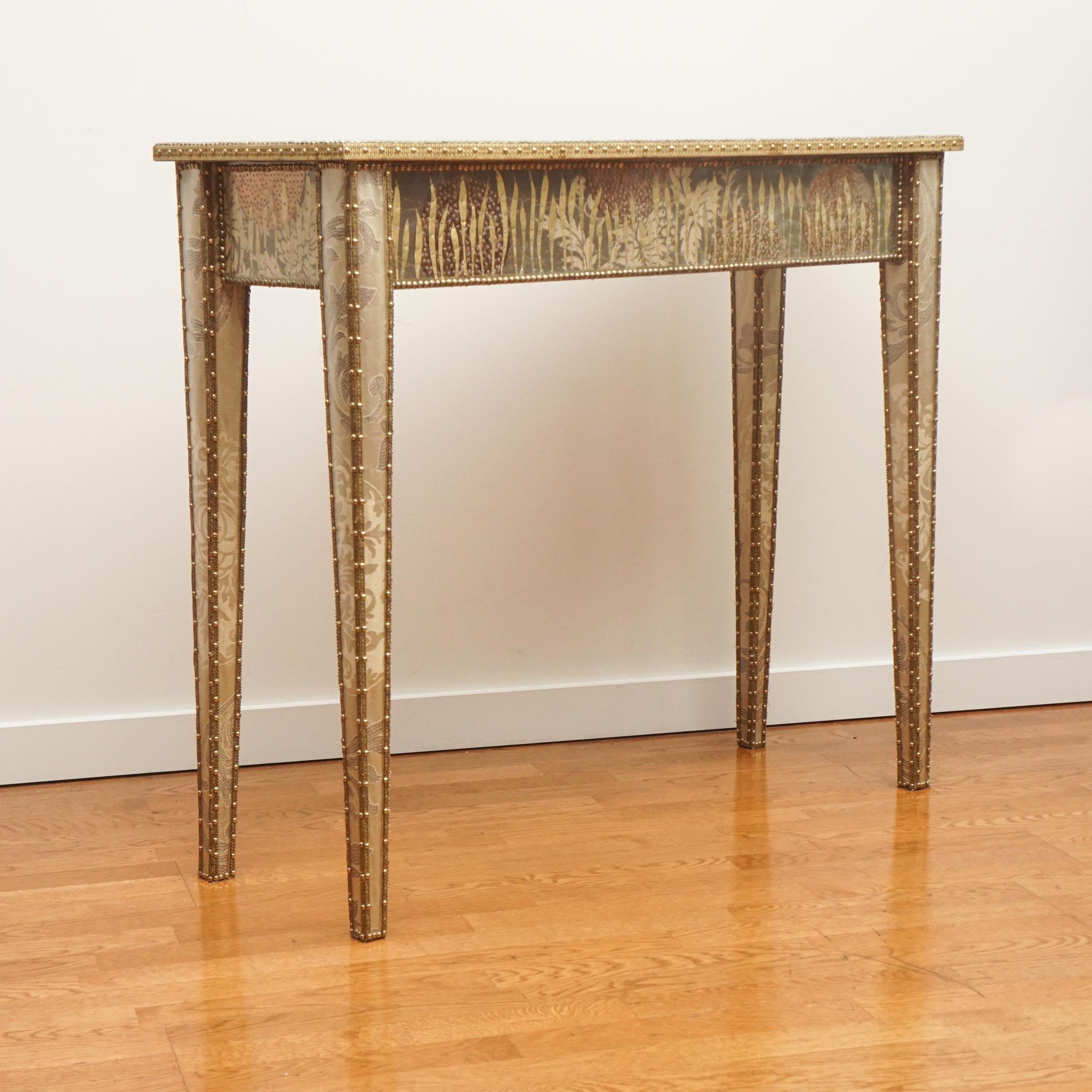 The Sutra console table is made of wood and covered with luxury fabric that is then hand decorated by Valentina Giovando with brass trimmings, large-round decorations made of brass and copper foil, sequins and hand-cut brass leaves. A final layer of