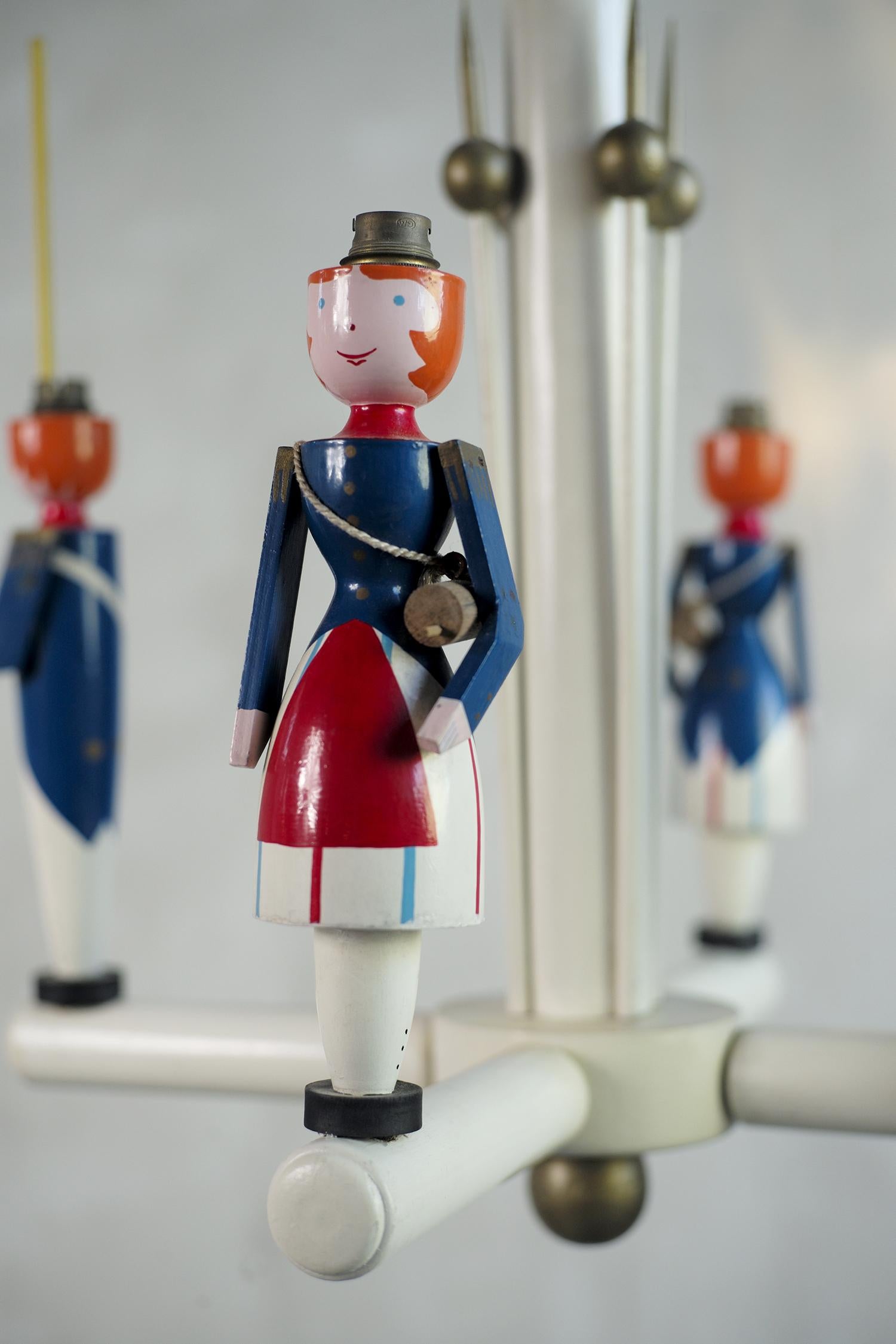 Suzanne Guiguichon/Gabriel Eglinger, lustre à 4 lumières en bois laqué édité par la Maitrise sous la direction de Maurice Dufrène, France 1926. D'une fraîcheur remarquable, cette lampe emblématique représente deux soldats et deux cantinières. Les