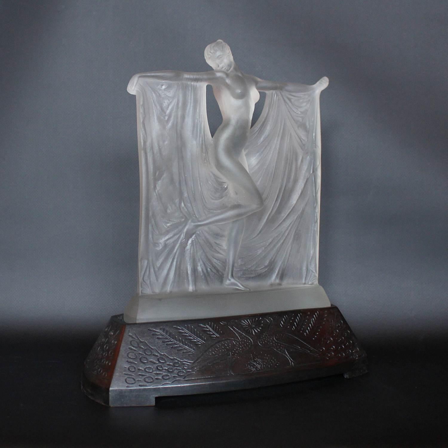 Suzanne, une figure de verre et de givre représentant une jeune femme légèrement drapée dans un tissu fluide. Elle est posée sur un socle en bronze moulé plus tardif.

R Lalique en relief à l'arrière. 




   