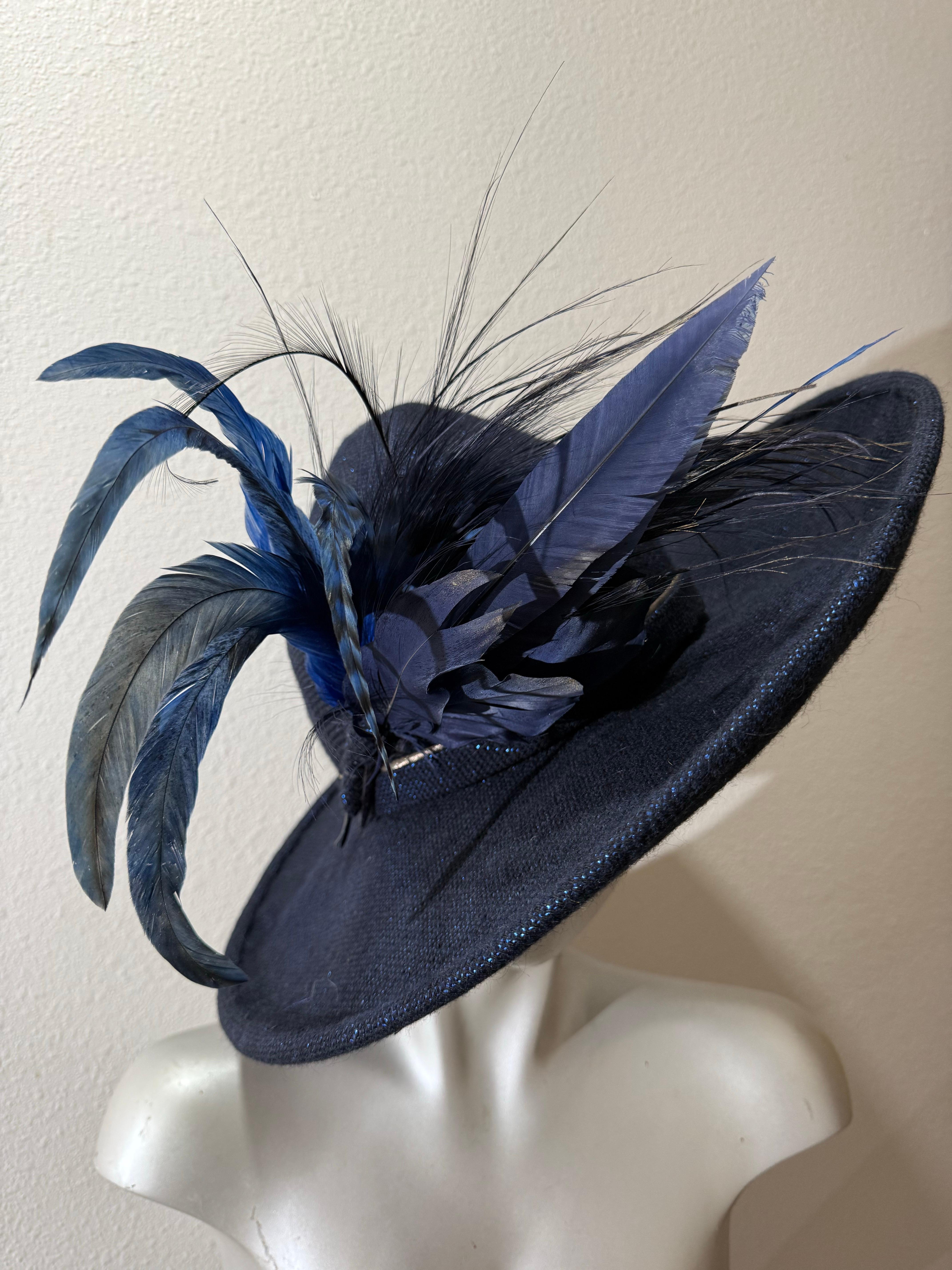 Suzanne Couture Millinery Fedora in lana blu navy e tessuto lurex con piume stravaganti:  Corona sagomata e sagomata, tesa larga strutturata e cablata. La piuma spray tinta in tinta è bellissima! Misure della tesa  17,5