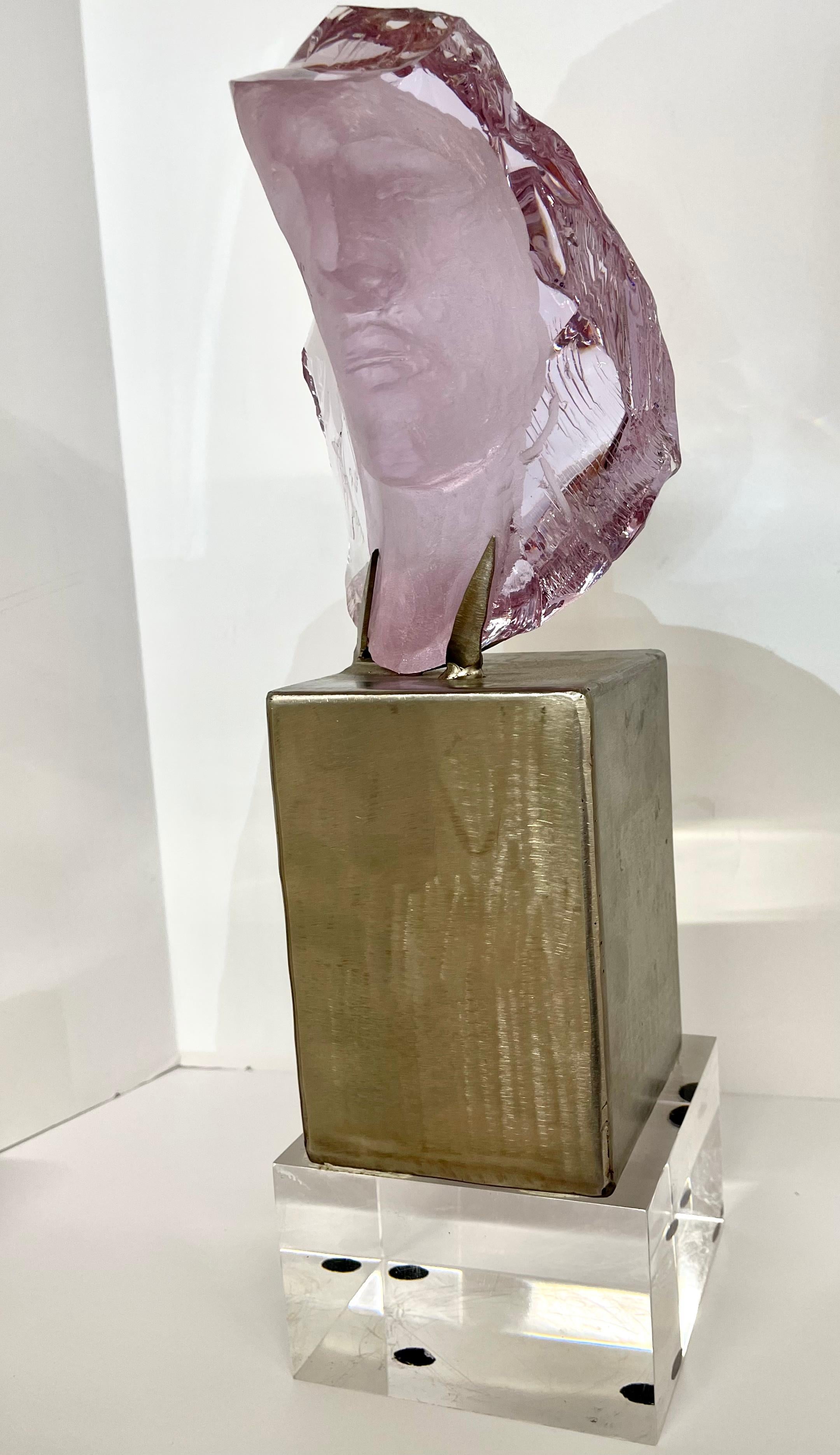 A wonderful carved purple carved slag glass bust by the noted California artist Suzanne Regan Pascal. Mounted on steel base with a lucite square affixed to the bottom. In good condition, with the exception of two surface scratches to one side of the