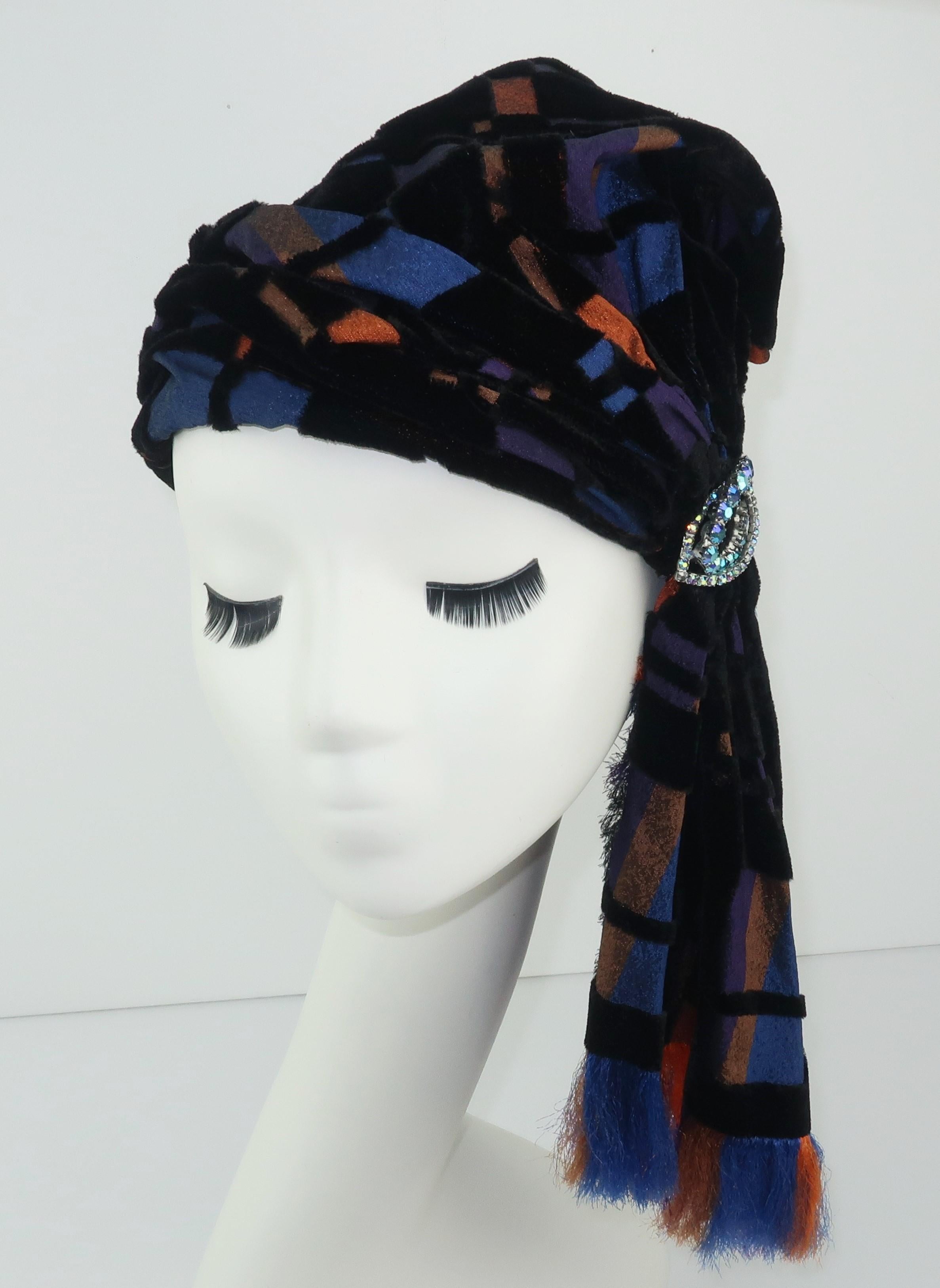 This turban shaped hat by Suzy Lee of California combines a bohemian style with a great plaid cut velvet in shades of black, copper orange, brilliant blue and plum.  The side drape has unfinished fringed edges by design and is accented by a