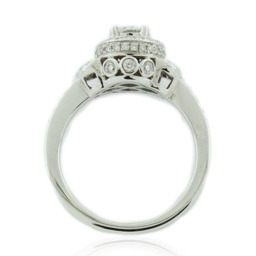 This spectacular ring from the Suzy Levian Limited Edition collection features a gorgeous round-cut, fancy white diamond (.47ct) (H-I, I2) center stone with an array of white diamond (.43cttw) accents, handset in a 14k white gold setting. French