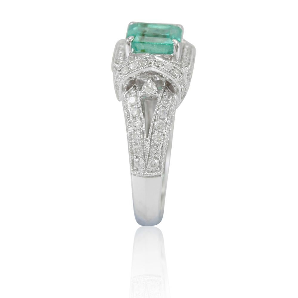 This spectacular ring from the Suzy Levian collection features a Colombian emerald gemstone held in a 14K white gold prong setting. An array of side white diamonds (1.04cttw) accents the perfect white gold color of the square cut center stone