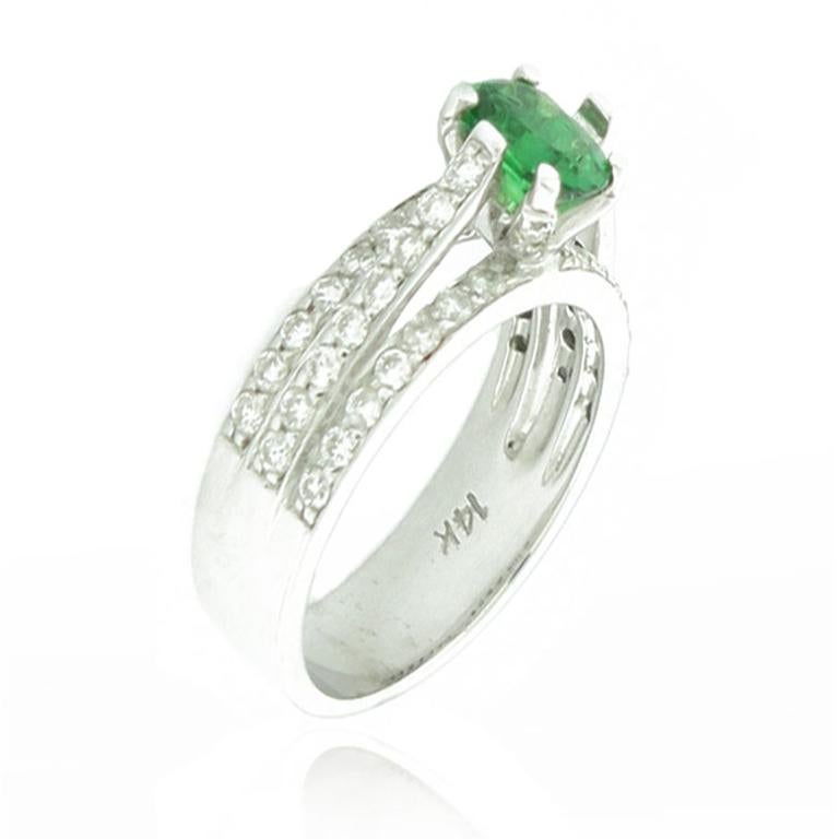 Cette bague spectaculaire de la collection Suzy Levian Limited Edition présente un or blanc 14k. Une magnifique rangée de diamants blancs (.98cttw) accentue le centre de cette parfaite pierre précieuse tsavorite verte de taille ovale (1.20ct). La