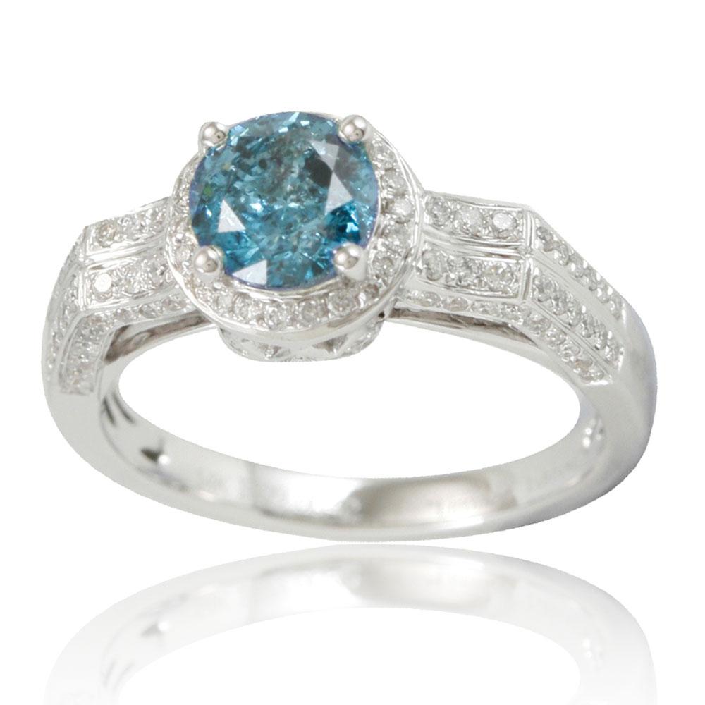 This stunning ring from the Suzy Levian Limited Edition collection features a gorgeous round-cut, rich blue diamond (1.12ct) center stone with an array of white diamond (.42cttw) accents, handset in a 14k white gold setting. French filigree